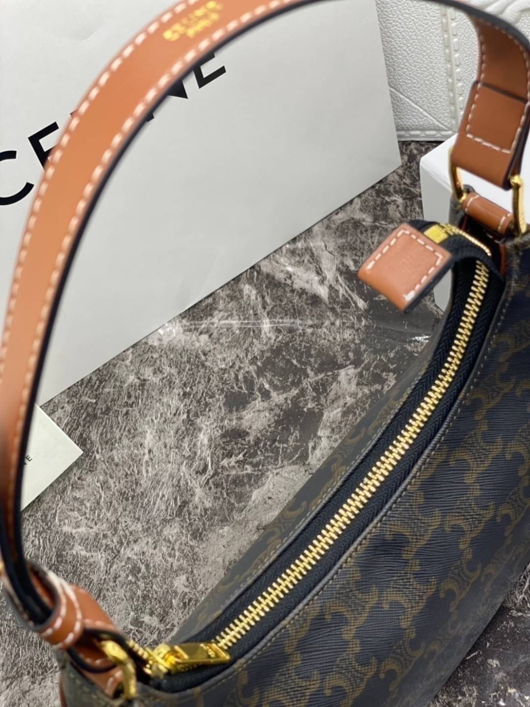 หนังแท้ CELINE AVA / CELINE Vintage Classic Ava bag 1 ใน คอลเลคชั่น “Triomphe Canvas” มาพร้อมสายสะพายไหล่ที่ปรับความยาวได้ และเนื่องจากช่วงล่างของกระเป๋ามีขนาดใหญ่กว่าช่วงบน จึงทำให้ไม่เสียทรงเมื่อเราใส่สิ่งของอย่างกระเป๋าสตางค์หรือโทรศัพท์มือถือ หากดูภาพ