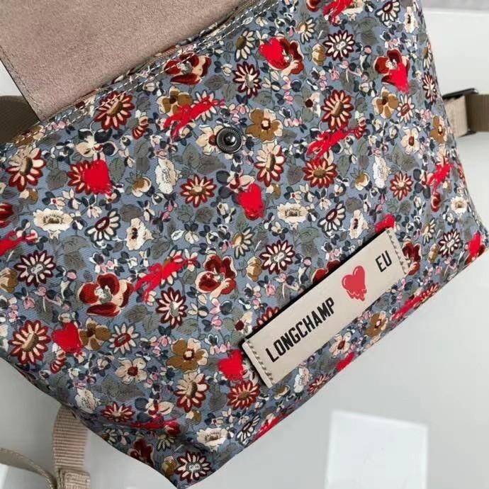 Longchamp X Eu Backpack กระเป๋าเป้สะพายหลังลายดอกๆไม้ วัสดุผ้าฝ้าย อะไหล่สีดำ กระเป๋าเป้แบบลำลองสำหรับสตรีซึ่งนำรูปทรงอันเป็นเอกลักษณ์ของ Le Pliage มาปรับใช้กับทุกสถานการณ์ อุปกรณ์เสริมที่ใช้งานได้จริงนี้มีสายรัดปรับระดับได้และที่จับช่วยให้ สะพายข้างหรือส