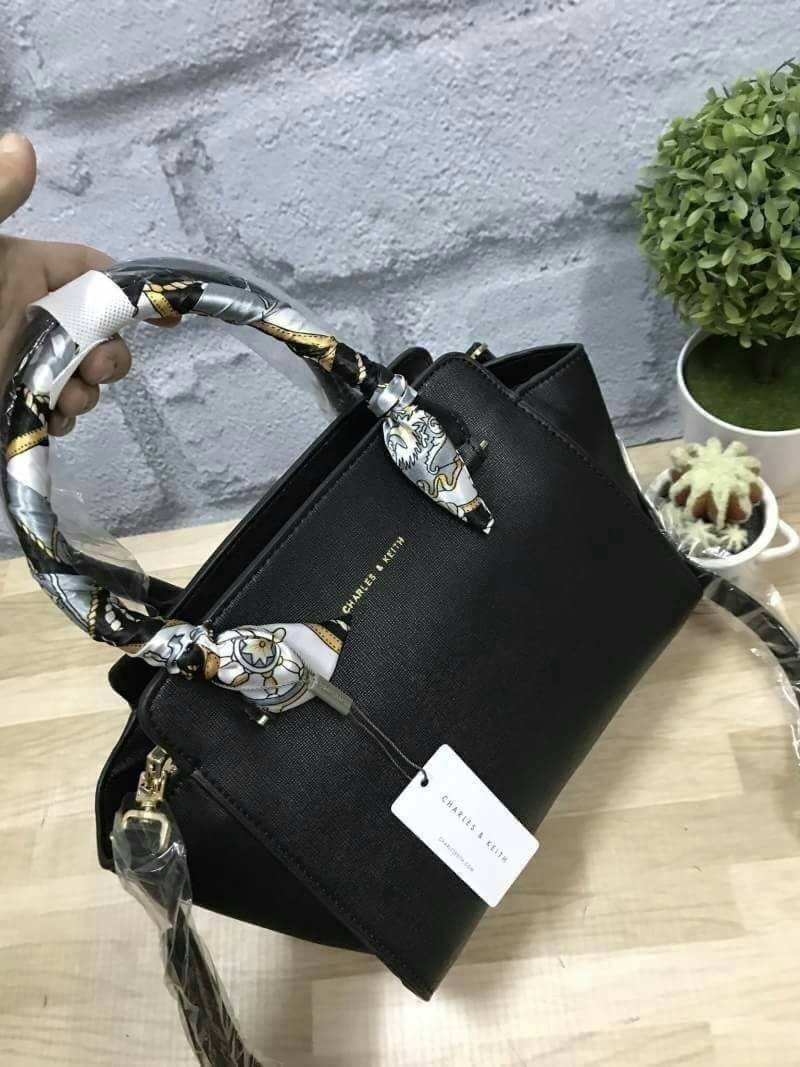 CHARLES&KEITH MINI TRAPEZ BAG พร้อมส่งรุ่นฮิตในตำนานรุ่นขายดี !! !กระเป๋าถือหรือสะพายหนังsaffiano พร้อมสายสะพายยาว115cmปรับความยาวได้5ระดับ ด้านล่างมีหมุดรองฐาน ทั้ง4มุม หูจับสูง14cmมีผ้าพันรอบสามารถถอดออกได้ ลายและสีสวยงามเข้ากับกระเป๋า ขนาดกำลังดีและน้ำ