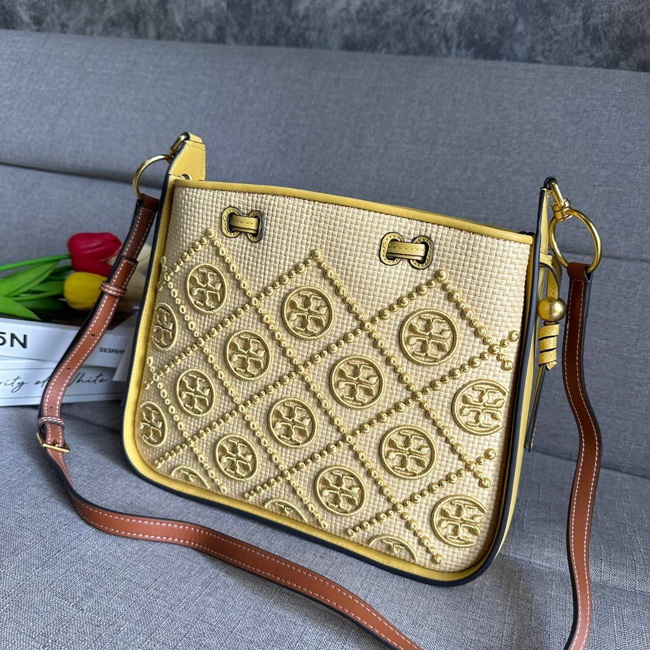 TORY BURCH T Monogram Straw Bell Bag กระเป๋าสะพายข้างรุ่นคลาสสิกที่ได้แรงบันดาลใจจากการควิลท์แบบดั้งเดิมของเพนซิลเวเนีย คอลเลกชันบ่งบอกถึงความมีสไตล์เหนือกาลเวลา รูปทรงเรียวโดดเด่น ปักทอลายแบรนด์อย่างสวยงาม เปิด ปิดด้วยเชือกรูด ด้านในช่องโล่งกว้าง ซับในผ้