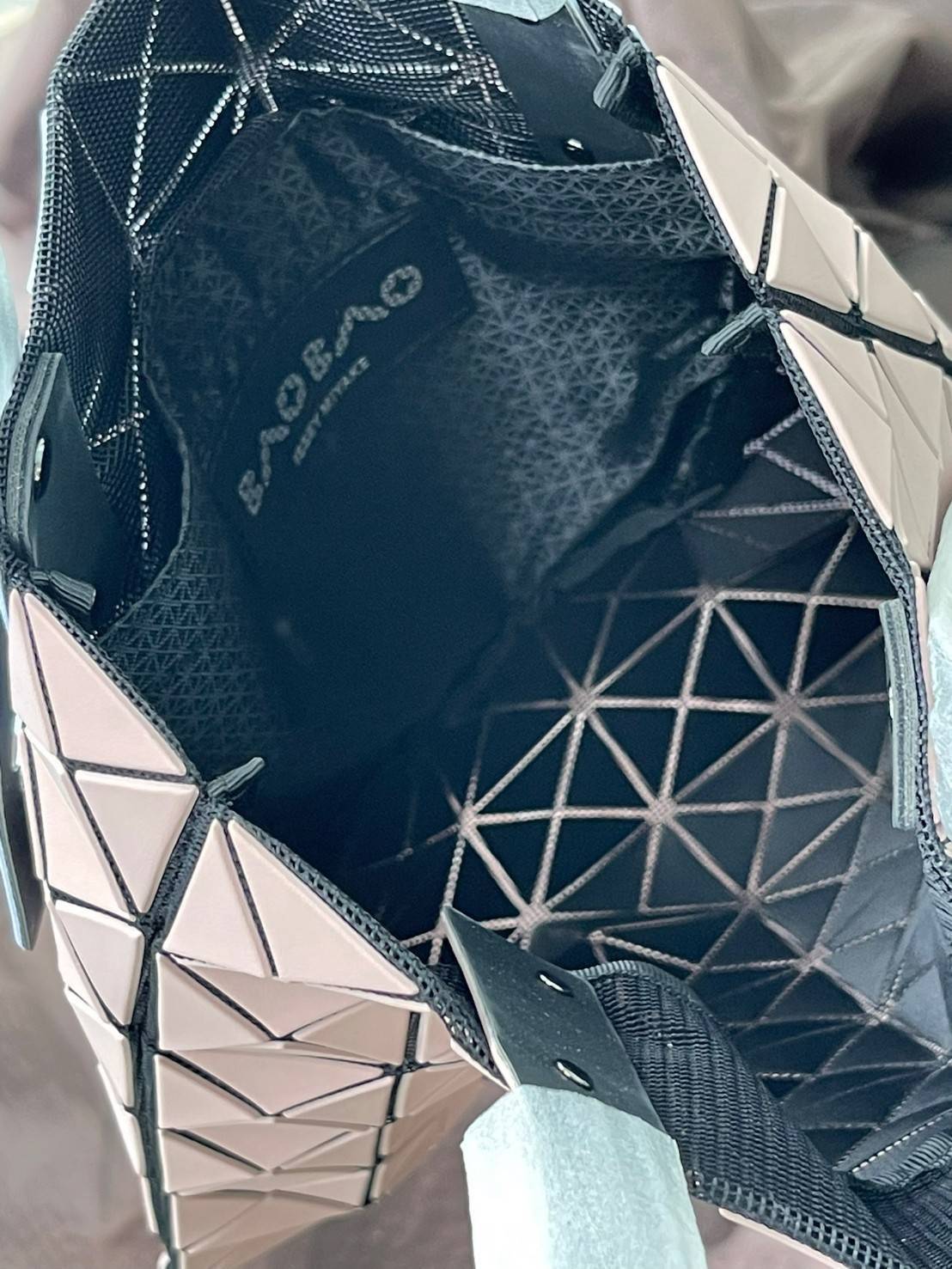 Baobao Issey Miyake Prism Kangaroo tote bag กระเป๋าถือทรงโท้ทที่ประดิษฐ์ขึ้นอย่างเชี่ยวชาญในญี่ปุ่น มาพร้อมแผงเรขาคณิตสำหรับการออกแบบที่ได้รับแรงบันดาลใจจากกระดาษพับ ซิลลูเอทอันเป็นเอกลักษณ์นี้ปิดท้ายด้วยสายรัดแบบอสมมาตร มีการพัฒนาโครงสร้างทรงสามเหลี่ยมเพ