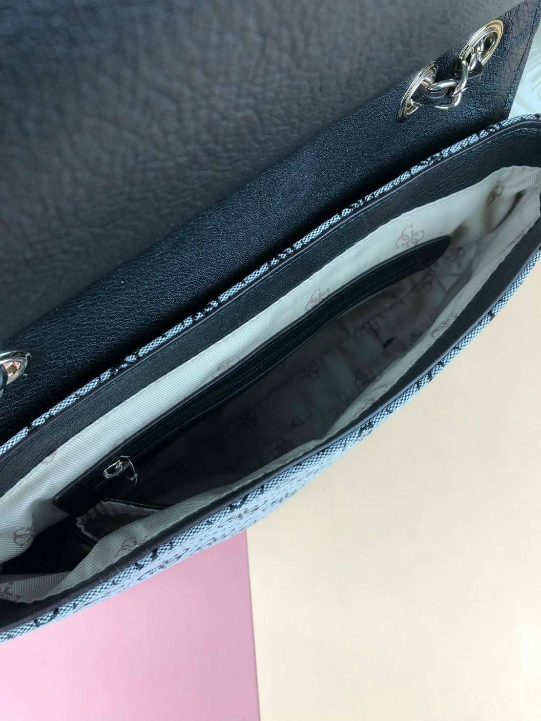 Guess Logo city handbag กระเป๋าสะพายไหล่ ตัวกระเป๋าเป็นผ้าลาย signature ของแบรนด์ ตัดกับหนังที่ตัวขอบกระเป๋า มาพร้อมพวงกุญแจโลโก้แบรนด์ ด้านหน้ามีโลโก้แบรนด์ ด้านหลังมีช่องใส่โทรศัพท์/บัตรได้ เปิดปิดแบบกระดุมแม่เหล็กซ้าย-ขวา ด้านในมีช่องซิป เล็ก 1 ช่อง แล