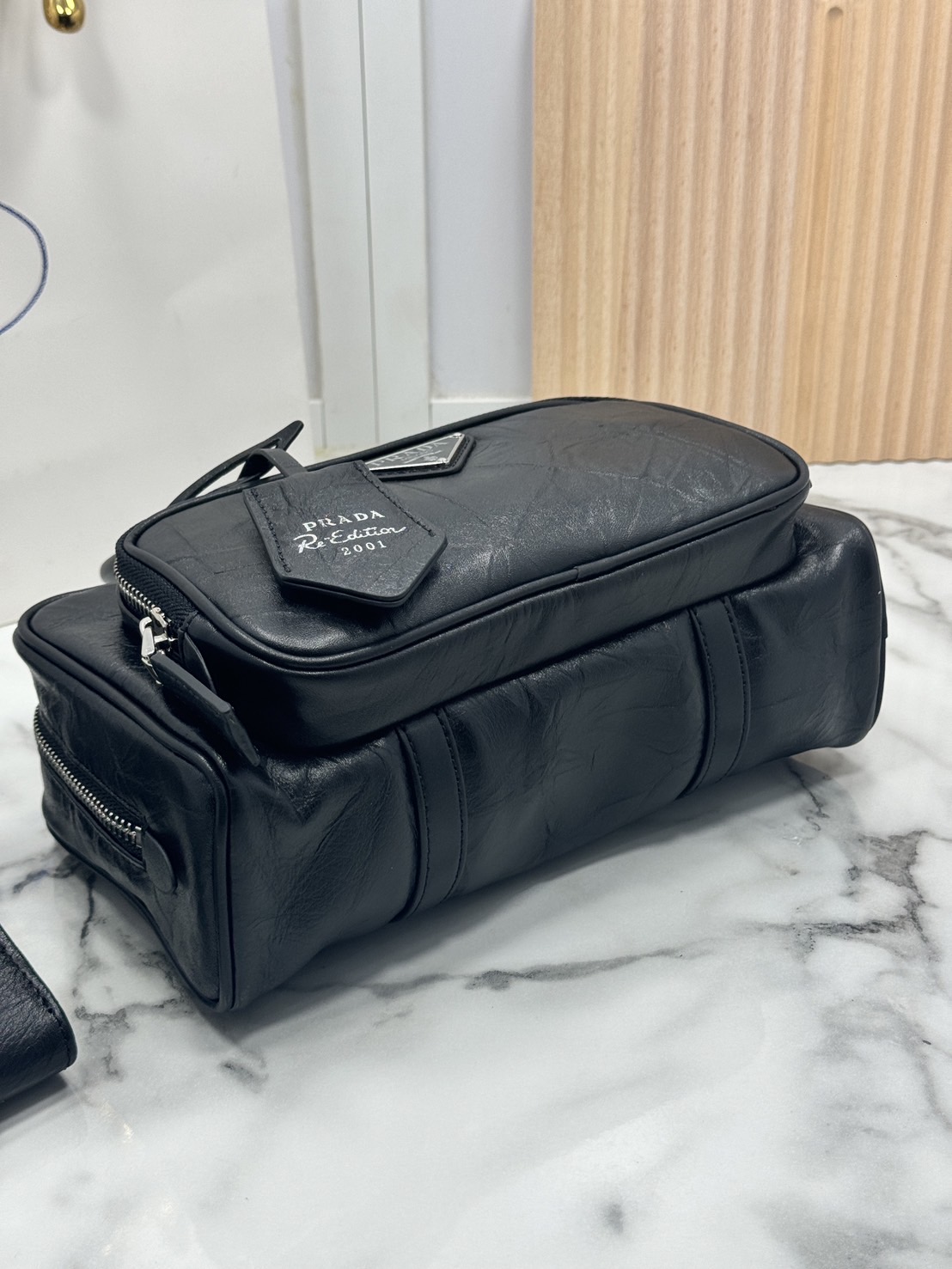 ORI หนังแท้ | Prada Antique nappa leather multi-pocket top-handle bag กระเป๋าสะพายทรง keepall มีช่องซิปด้านหน้าพร้อมหูจับ งานหนังยับดีไซน์เอฟเฟกต์เท็กซ์เจอร์ที่มีเสน่ห์สไตล์วินเทจ พร้อมทริกห้อยเพิ่มสไตล์สัมผัสที่โดดเด่นและร่วมสมัยยิ่งขึ้น