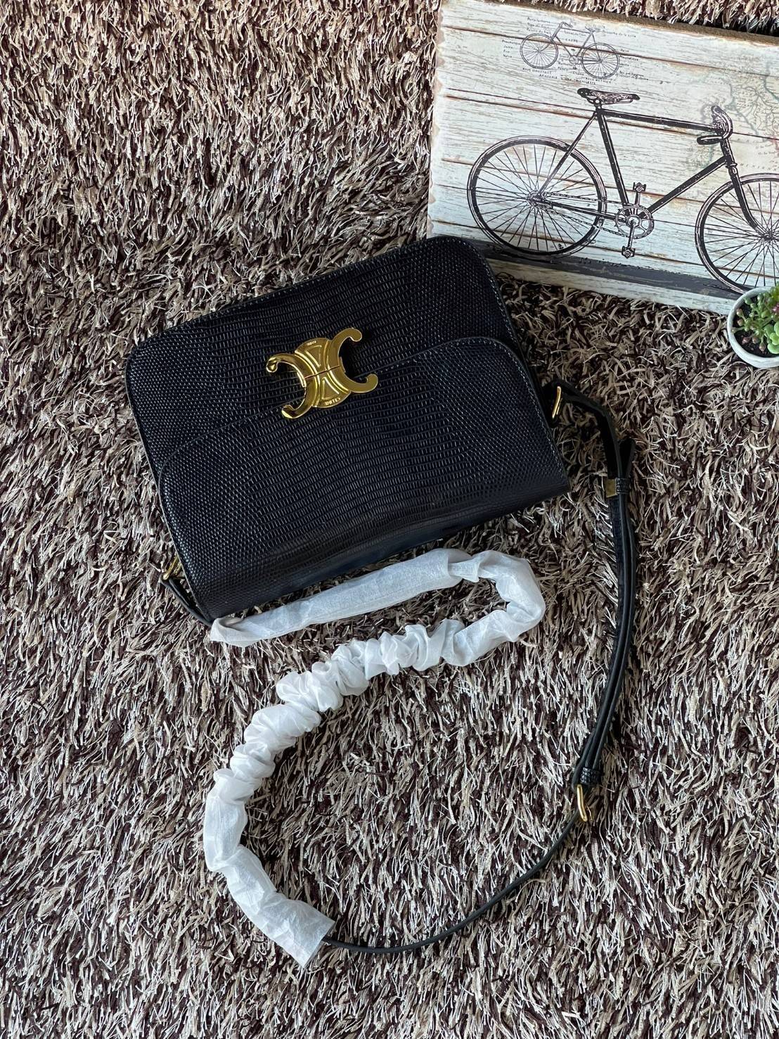 Celine MEDIUM TRIOMPHE BAG IN SHINY By croc มีรูปทรงเป็นกล่องคล้ายกับกระเป๋า Classic Box แต่มีการออกแบบโลโก้ที่สะดุดตาแบบวินเทจ ด้วยดีไซน์หรูหราและที่ดูโฉบเฉี่ยวเ้วยลงดลายcroc มีความคลาสสิคอย่างเต็มเปี่ยม ทำให้เป็นที่ดึงดูดความสนใจของสาวๆ ด้วยความคล่องตัว