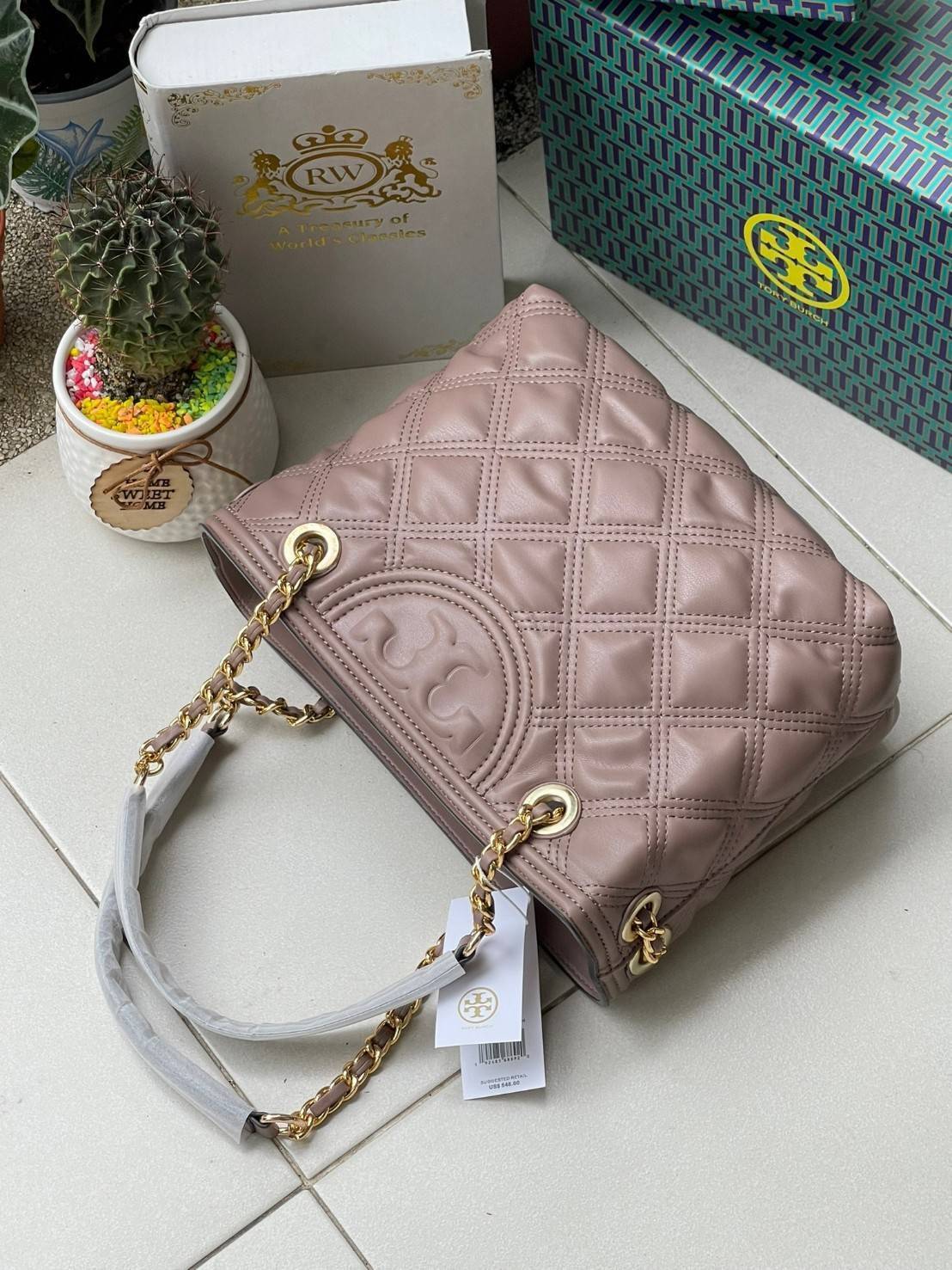Tory Burch Fleming Soft Small Tote Bag เป็นกระเป๋าสะพายไหล่น่ารัก ๆ สักใบที่มีดีไซน์โดดเด่น สะดุดตา ใน Collection เรียกได้ว่าขายดีอันดับต้น ๆ ของแบรนด์ ใช้ได้ในลุคช์ทางการและกึ่งทางการ ดีเทลการตัดเย็บพิมพ์ลายนูนคู่กับแพทเทิร์นสี่เหลี่ยมทรงเพชร ที่ช่วยเพิ่