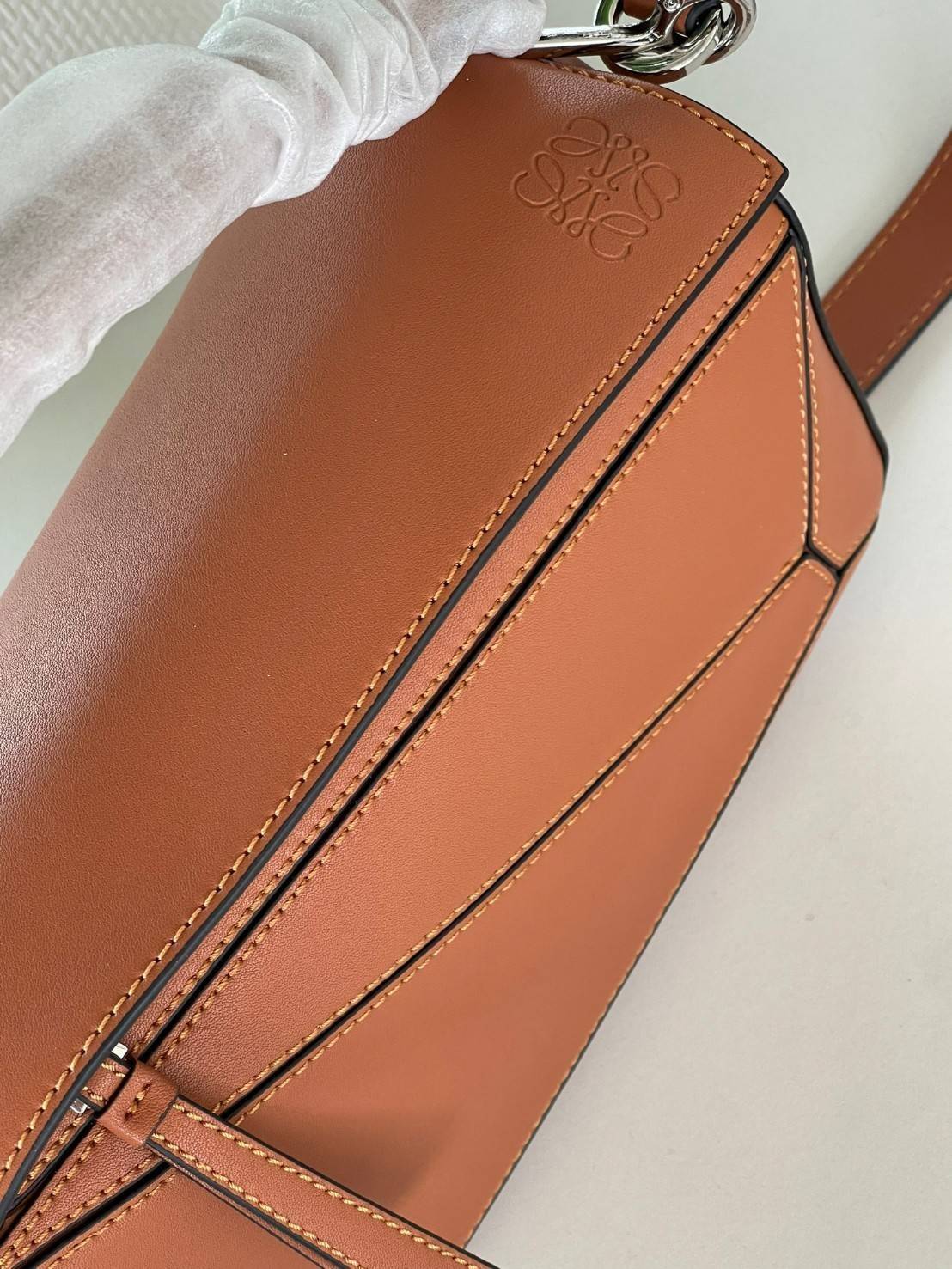 Loewe Puzzle Bag In Classic กระเป๋าทรง Puzzle นี้ออกแบบโดย Jonathan Anderson โดยได้รับแรงบันดาลใจในการออกแบบมาจากรูปทรงของลูกรักบี้ ดังนั้น จึงจะเห็นได้ว่าการตัดเย็บและรูปทรงของกระเป๋านั้นคล้ายคลึงกับลูกรักบี้ รูปทรงดูมินิมอลไม่ทิ้งคอนเซ็ปต์ของแบรนด์ สามา