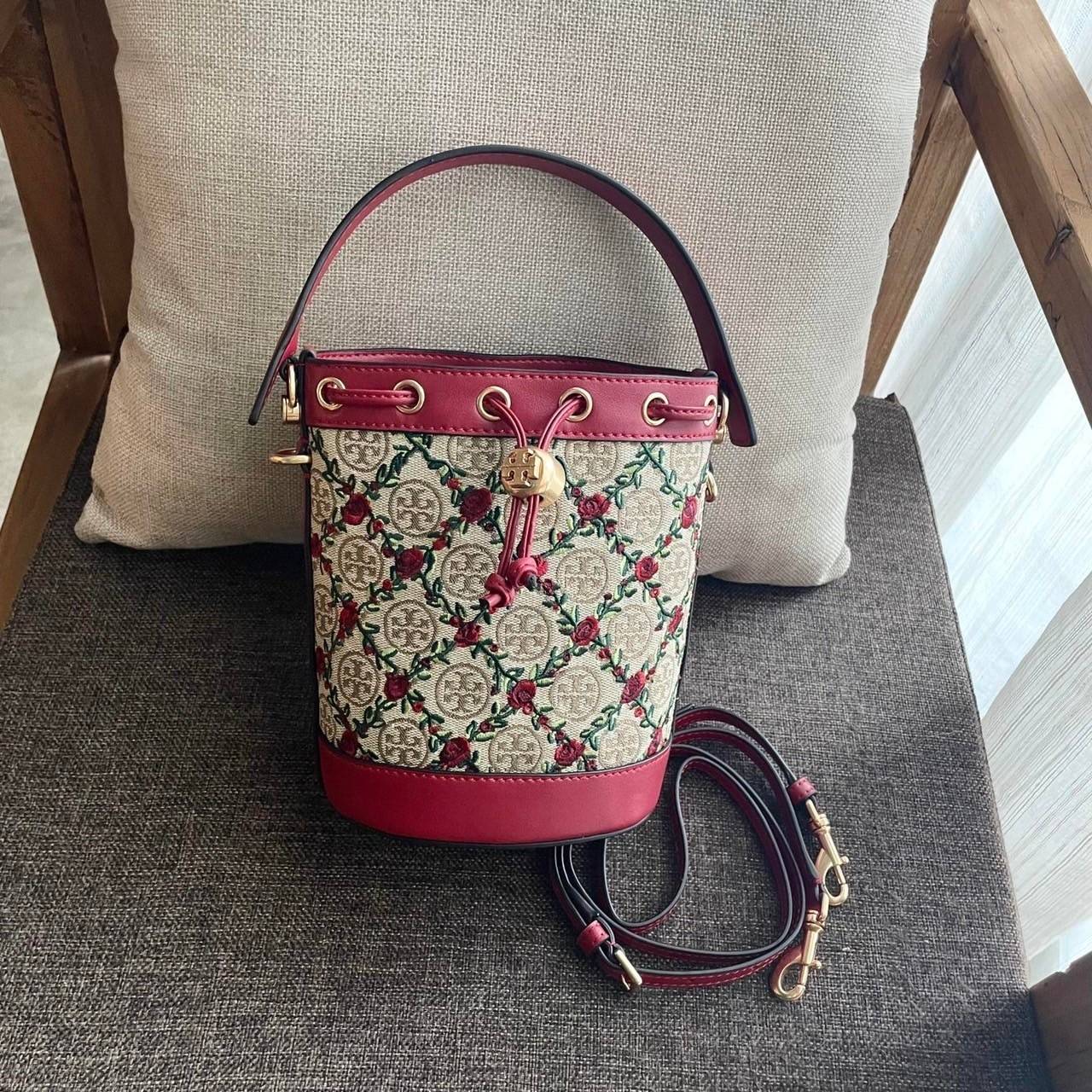 Mini : Tory Burch T Monogram Embroidered Mini Bucket Bag Hazelnut กระเป๋าทรงถังขนาดเล็ก เป็นแพทเทิร์นคลาสสิคที่ได้รับแรงบันดาลใจจากการควิลท์แบบดั้งเดิมของเพนซิลเวเนีย คอลเล็คชั่นบอกเล่าความมีสไตล์เหนือกาลเวลา ลายดอกกุหลาบสีแดงลายปักษ์ วัสดุผ้าสว๊อตซ์วินเท