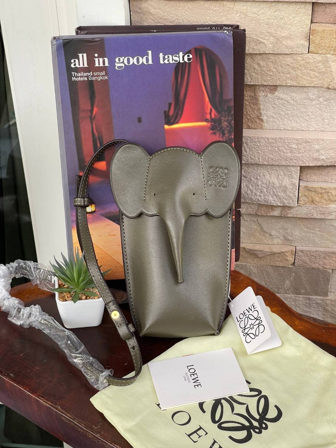 Loewe Leather Elephant Phone Holder แบรนด์หรูจากประเทศสเปนอย่าง โลเอเว่ (LOEWE) หลายๆคนคงนึกถึงกระเป๋ารูปทรงช้างขนาดเล็ก ที่เป็นเหมือนหนึ่งในซิกเนเจอร์ของแบรนด์ มีทั้งแบบสะพายข้าง แบบถือ รวมไปถึงในแบบเครื่องหนังชิ้นเล็กอย่างกระเป๋าใส่มือถือรุ่นนี้ ผลิตจาก
