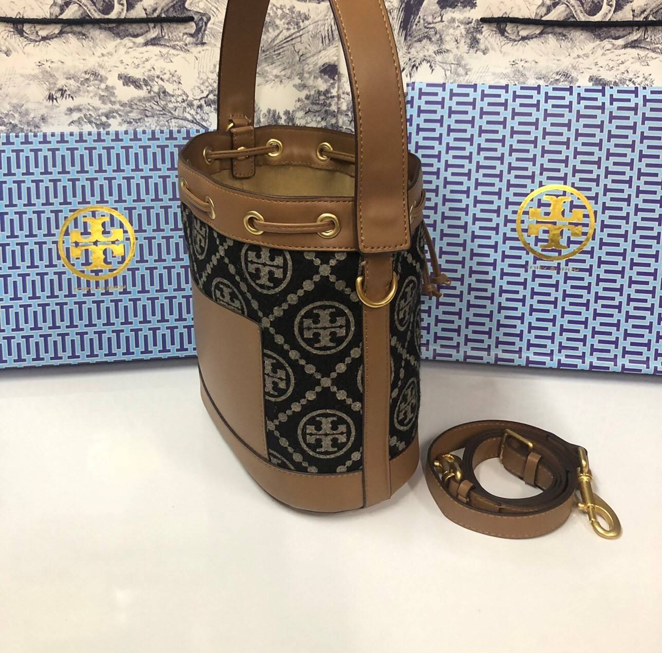 Medium : Tory Burch T Monogram Chenille Bucket Bag เปิดตัวอีกหนึ่งรุ่นกับกระเป๋าลาย T MONOGRAM รุ่นใหม่ล่าสุดจาก TORY BURCH พลาดไม่ได้กับโลโก้สุดคลาสสิก ลวดลาย T Monogram คือวัสดุ chenille หรือที่เรียกว่า ด้านไหมกำมะหยี่ มารังสรรค์ลงบนกระเป๋าBucketใบนี้ เ