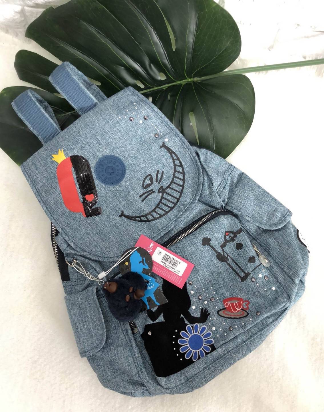 Kipling Disney's Alice in Wonderland Printed Backpack กระเป๋าเป้ Limited คอลเลคชั่น ALICE วัสดุ Denim+Polyester 100% เปิดปิดด้วยฝาปิด กระดุมแม่เหล็ก และซิปรอบ มาพร้อมพวงกุญเเจลิง ถอดเเยกใช้ได้ มีช่องซิปด้านหน้า และด้านหลัง พร้อมช่องใส่ของด้านข้าง 2 ด