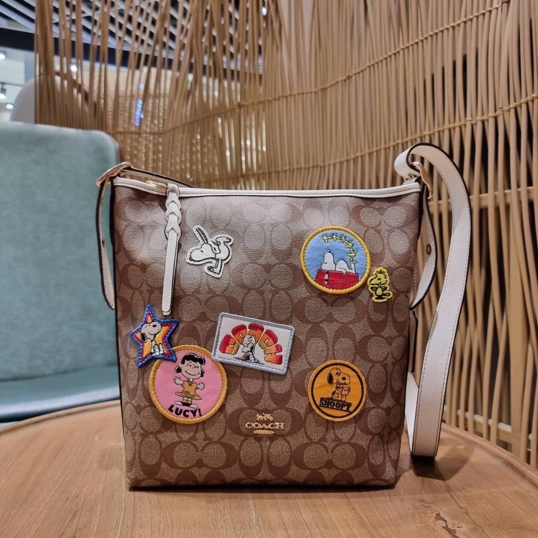 OUTLET 】COACH C4112 COACHxPEANUTS VAL DUFFLE IN SIGNATURE CANVAS WITH VARSITY PATCHES ใหม่ล่าสุด กระเป๋าทรงดัฟเฟิล ที่มาพร้อมเหล่าผองเพื่อนสนูปพี สวยมีเอกลักษณ์ ทรงกระเป๋าไม่ซ้ำใคร แถมยังใส่ของได้จุใจไปอีก วัสดุหนังแคนวาสคุณภาพดี ด้านหลังมีช่องซิป กระเป๋า