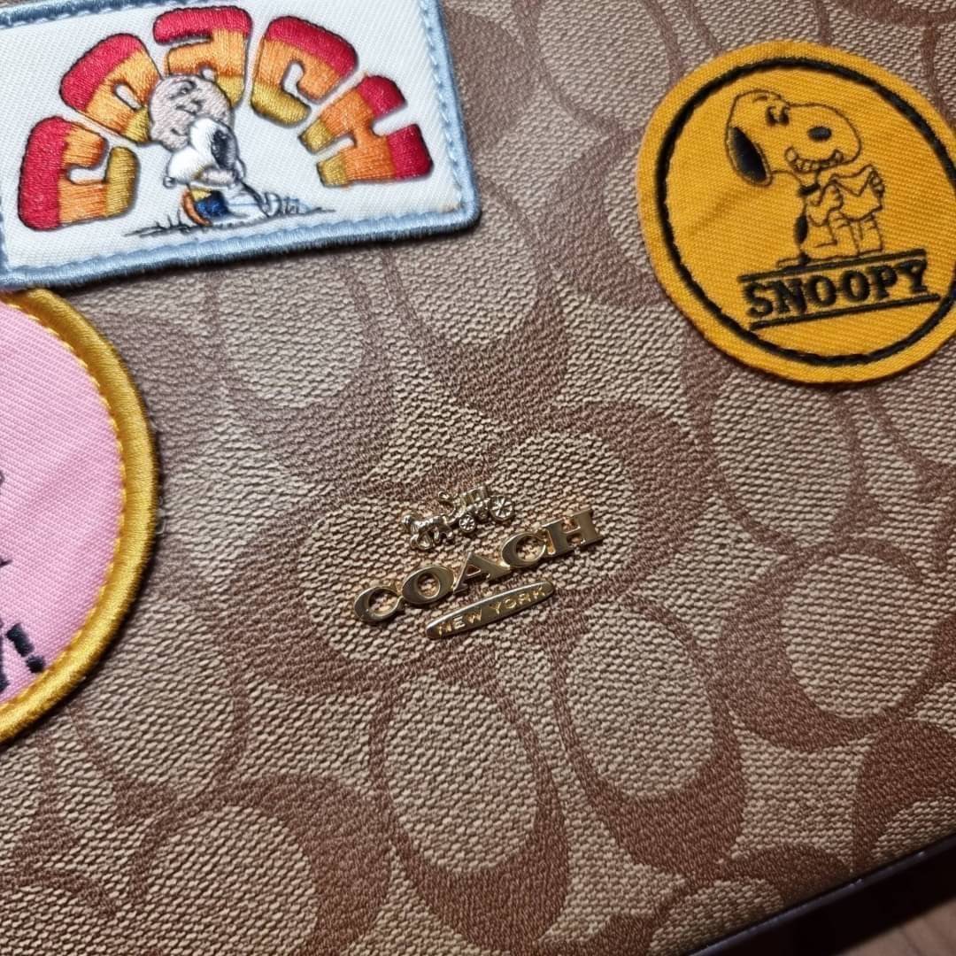 OUTLET 】COACH C4112 COACHxPEANUTS VAL DUFFLE IN SIGNATURE CANVAS WITH VARSITY PATCHES ใหม่ล่าสุด กระเป๋าทรงดัฟเฟิล ที่มาพร้อมเหล่าผองเพื่อนสนูปพี สวยมีเอกลักษณ์ ทรงกระเป๋าไม่ซ้ำใคร แถมยังใส่ของได้จุใจไปอีก วัสดุหนังแคนวาสคุณภาพดี ด้านหลังมีช่องซิป กระเป๋า