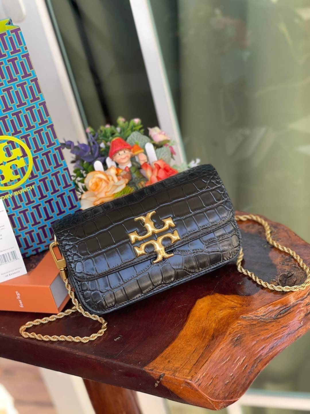 Tory Burch Eleanor Crocodile-Embossed Phone Crossbody Bag จุดเด่นของรุ่นนี้คือดีไซน์ออกมาในสไตล์คลาสสิกที่มาพร้อมกับฮาร์ดแวร์ที่ทำจากวัสดุทองเหลืองและสายสะพายโซ่เกลียวสีทอง ซึ่งการออกแบบได้รับแรงบันดาลใจมาจากเครื่องประดับ รูปทรงกะทัดรัดจึงสามารถสะพายใช้งา