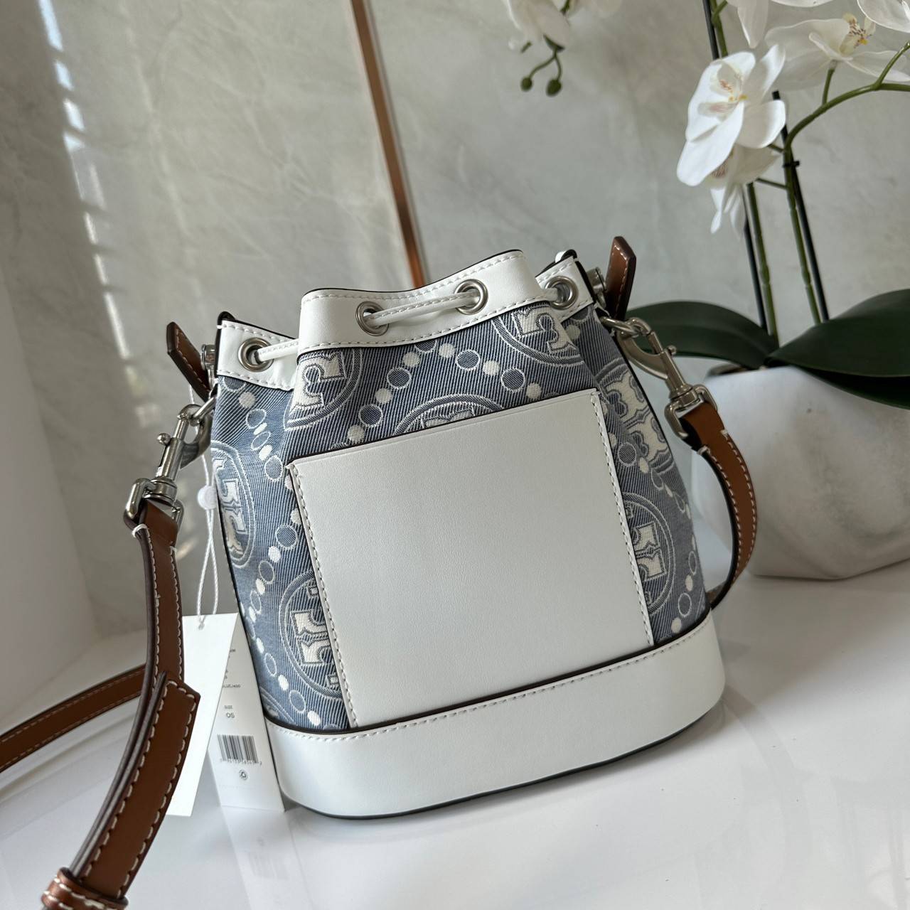 TORY BURCH T Monogram Denim Bucket Bag MEDIUM คอลเลคชั่นใหม่ รูปแบบคลาสสิค พกพาความหรูหราไปได้ทุกที่ด้วยกระเป๋าทรง Bucket ขนาดกลางและปิดด้วยเชือกรูดพร้อมโลโก้แวววาว วัสดุผ้าเดนิมแจ็คการ์ด ตัดขอบหนังแท้