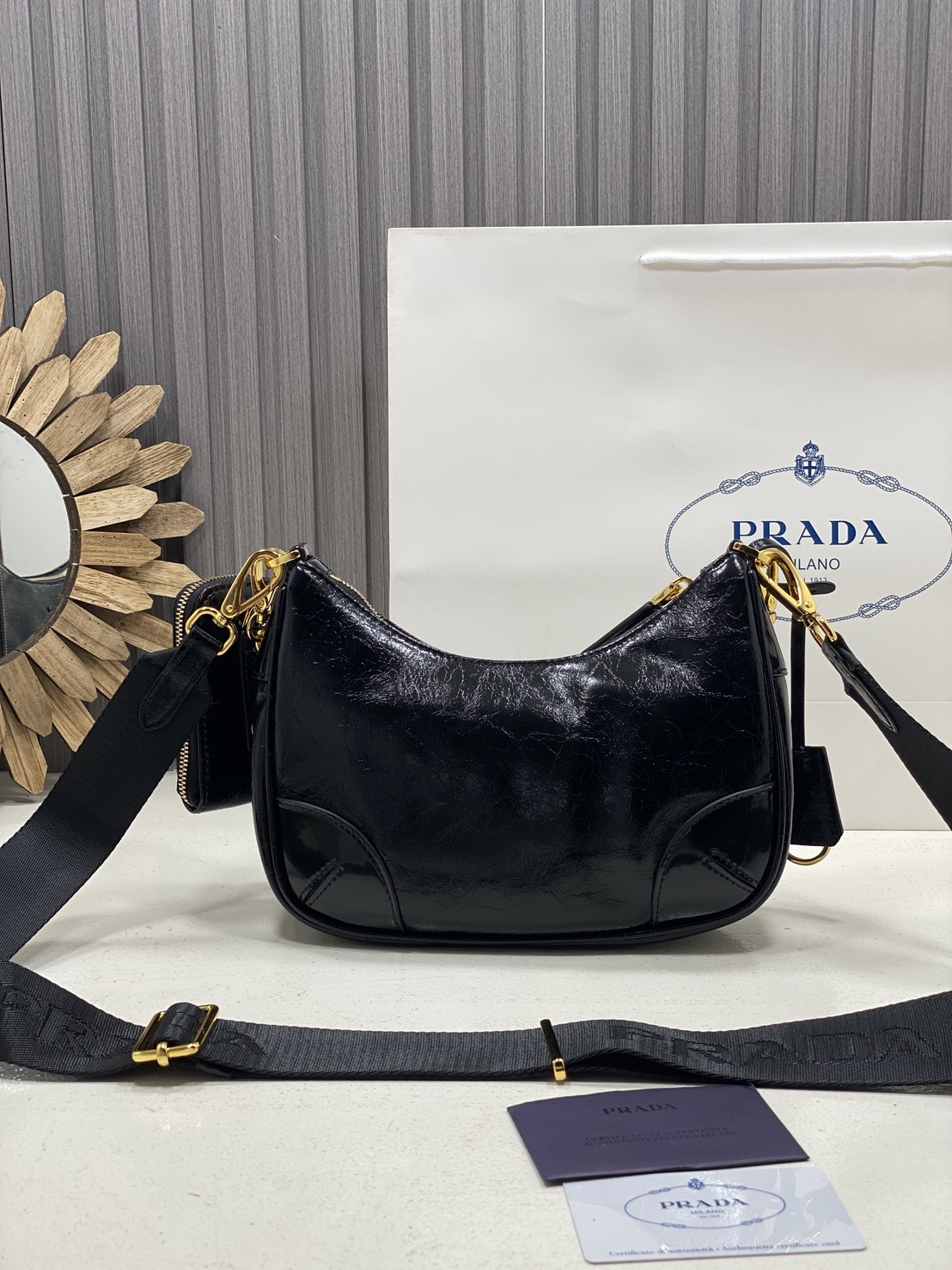 ORI หนังแท้ | Prada Re-Edition 2005 bag in Naplak leather กระเป๋าสะพายทรงโฮโบหนังแก้ว ดีไซน์เอฟเฟกต์มันวาวและเท็กซ์เจอร์ที่มีเสน่ห์สไตล์วินเทจ พร้อมทริกห้อยเพิ่มสไตล์สัมผัสที่โดดเด่นและร่วมสมัยยิ่งขึ้น