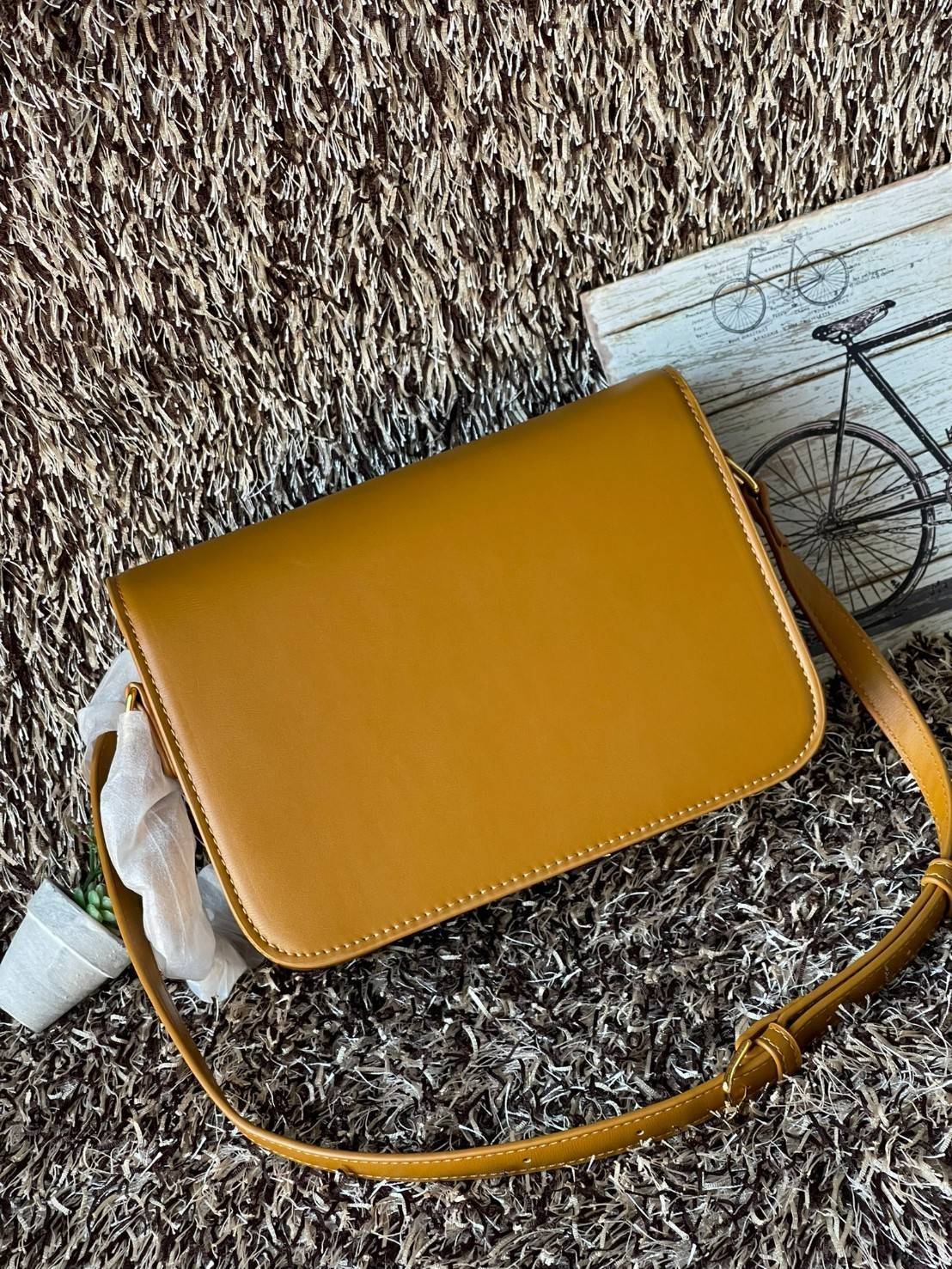 Celine MEDIUM TRIOMPHE BAG IN SHINY มีรูปทรงเป็นกล่องคล้ายกับกระเป๋า Classic Box แต่มีการออกแบบโลโก้ที่สะดุดตาแบบวินเทจ ด้วยดีไซน์ที่ดูโฉบเฉี่ยว แต่คงความคลาสสิคอย่างเต็มเปี่ยม ทำให้เป็นที่ดึงดูดความสนใจของสาวๆ สายสะพายสามารถปรับระดับได้ มีความคล่องตัวในก