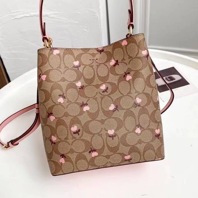OUTTLET 】COACH SMALL TOWN BUCKET BAG IN SIGNATURE WITH Heart floral print สำหรับสาวแฟชั่นที่ชอบรายละเอียดชิคๆ ดีไซน์สุดเก๋ แนะนำเลยสำหรับกระเป๋าทรงบักเก็ตใบนี้ เชื่อว่าสาว ๆ หลายคนชื่นชอบ เป็นไอเทมที่สามารถแมทช์ได้กับเสื้อหลากหลายสไตล์ บรรจุของได้เยอะโดยท
