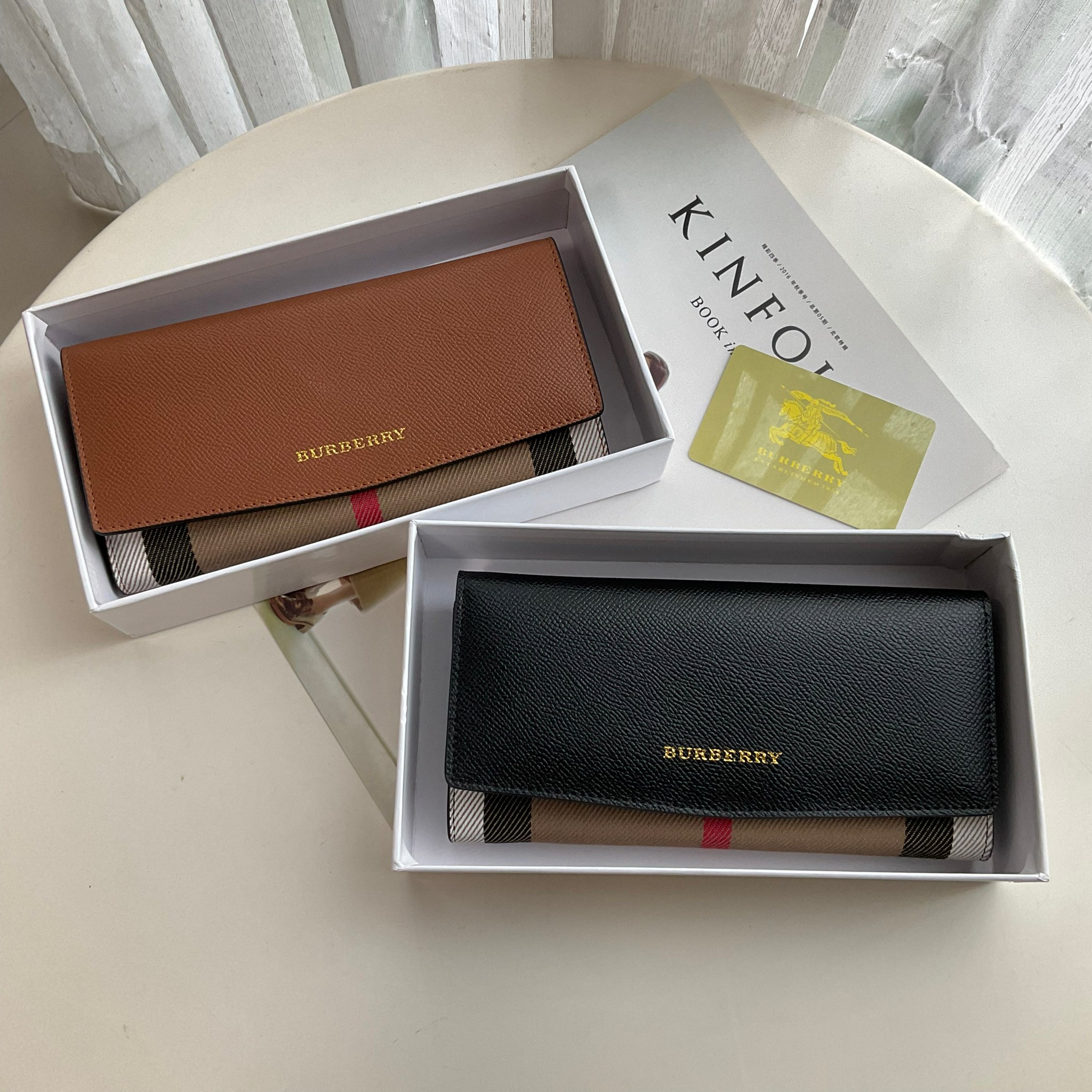 กระเป๋าสตางค์รับทรัพย์ ทรงหรู จากงาพรีเมี่ยมกิ๊ฟ Limited Edition จาก BURBERRY กระเป๋าสตางค์ใบยาวแบบพับกระดุม ทูโทนด้วยหนังแท้คาดผ้าลาย vintage ด้านในมีช่องใส่ธนบัตรยาวทั้งสองฝั่ง ช่องใส่บัตรได้อย่างน้อย 12 ช่อง และช่องเปิดด้วยซิปปั้มแบรนด์อะไหล่ทองสุดหรู 