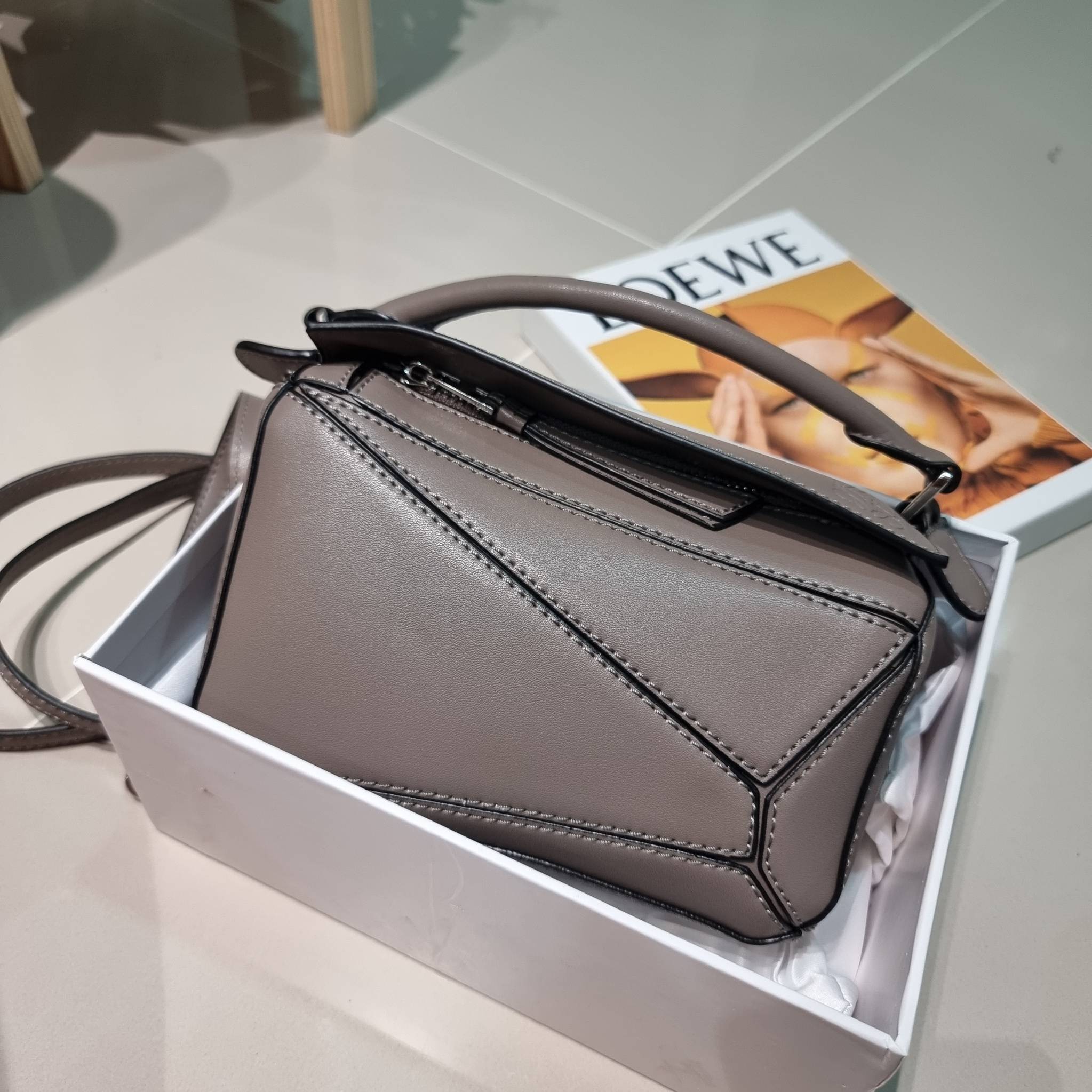 LOEWE MINI PUZZLE BAG IN CLASSIC สุดยอดแบรนด์ที่ดีไซน์เป็นเอกลักษณ์ โดดเด่น สวยหรู กับกระเป๋าสะพายข้างทรงกล่อง ไซส์มินิ สไตล์พัซเซิล ให้ฟีลลิ่งเหมือนตัวต่อคละสี ดูดีได้ทุกที่แค่มีใบนี้