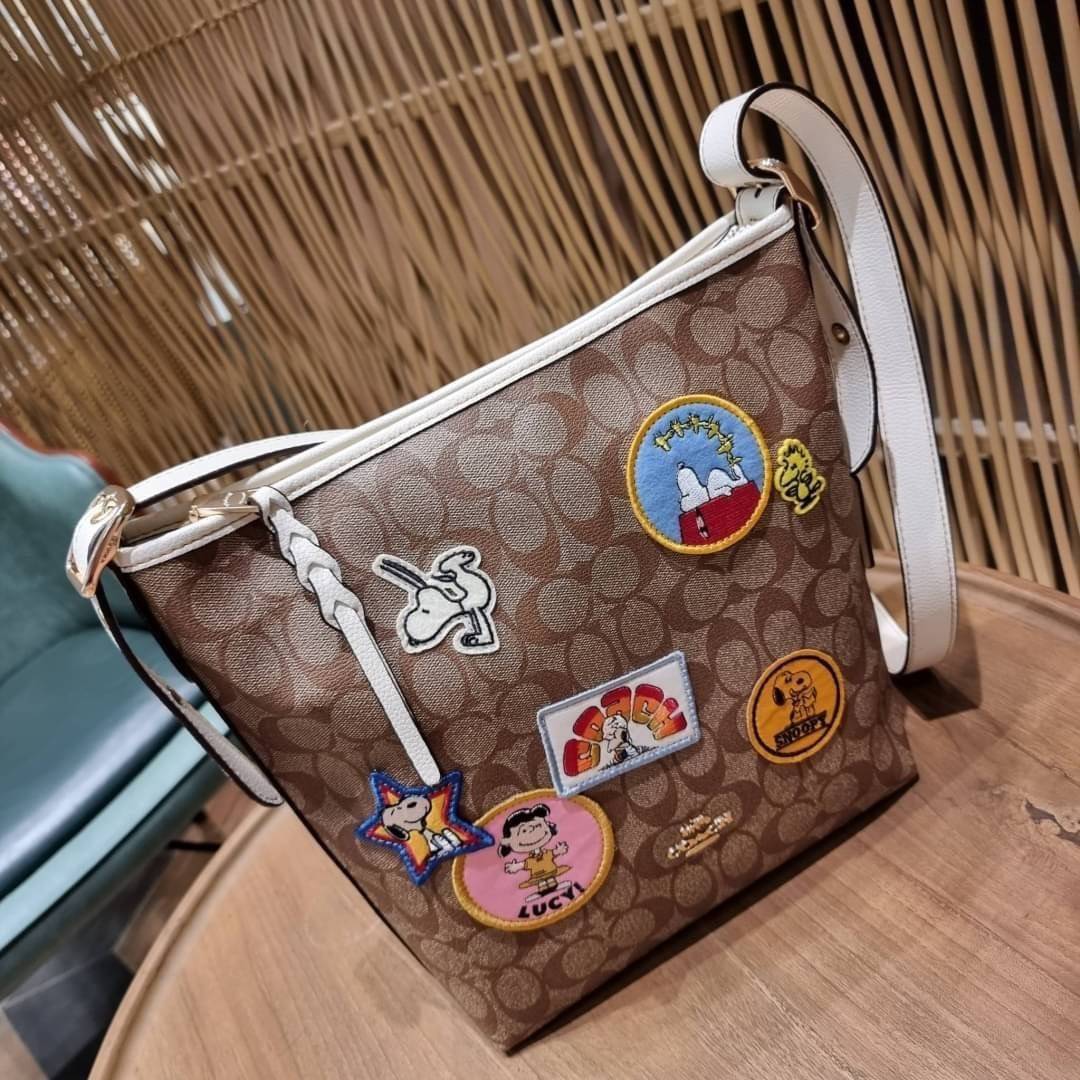 OUTLET 】COACH C4112 COACHxPEANUTS VAL DUFFLE IN SIGNATURE CANVAS WITH VARSITY PATCHES ใหม่ล่าสุด กระเป๋าทรงดัฟเฟิล ที่มาพร้อมเหล่าผองเพื่อนสนูปพี สวยมีเอกลักษณ์ ทรงกระเป๋าไม่ซ้ำใคร แถมยังใส่ของได้จุใจไปอีก วัสดุหนังแคนวาสคุณภาพดี ด้านหลังมีช่องซิป กระเป๋า