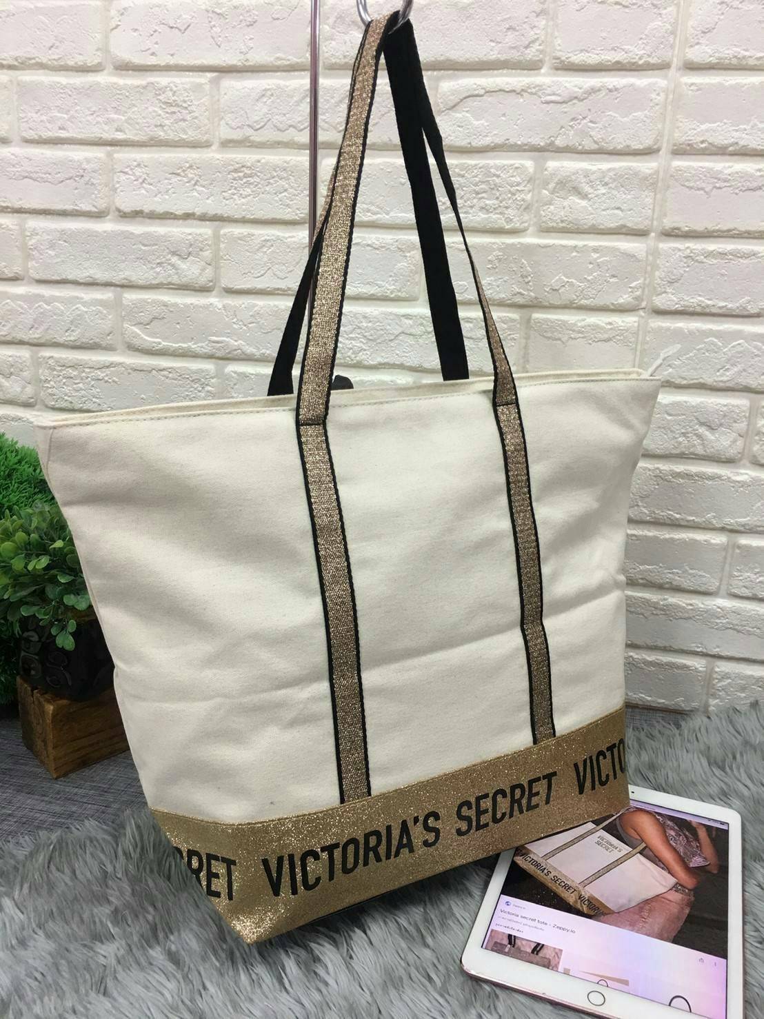 Victoria's Secret Canvas Tote Bag กระเป๋าสะพายวัสดุแคสวาสสีครีม ด้านล่างเป็นกลิตเตอร์ สกรีนชื่อแบรนด์ ฐานกระเป๋าเป็นหนัง ด้านหน้ามีช่องเล็กไว้ใส่ของได้ เปิดปิดด้วยซิป ซับในลายแบรนด์ มีช่องซิปเล็กแยกใส่ของ1ช่อง จุของได้เยอะมาก
