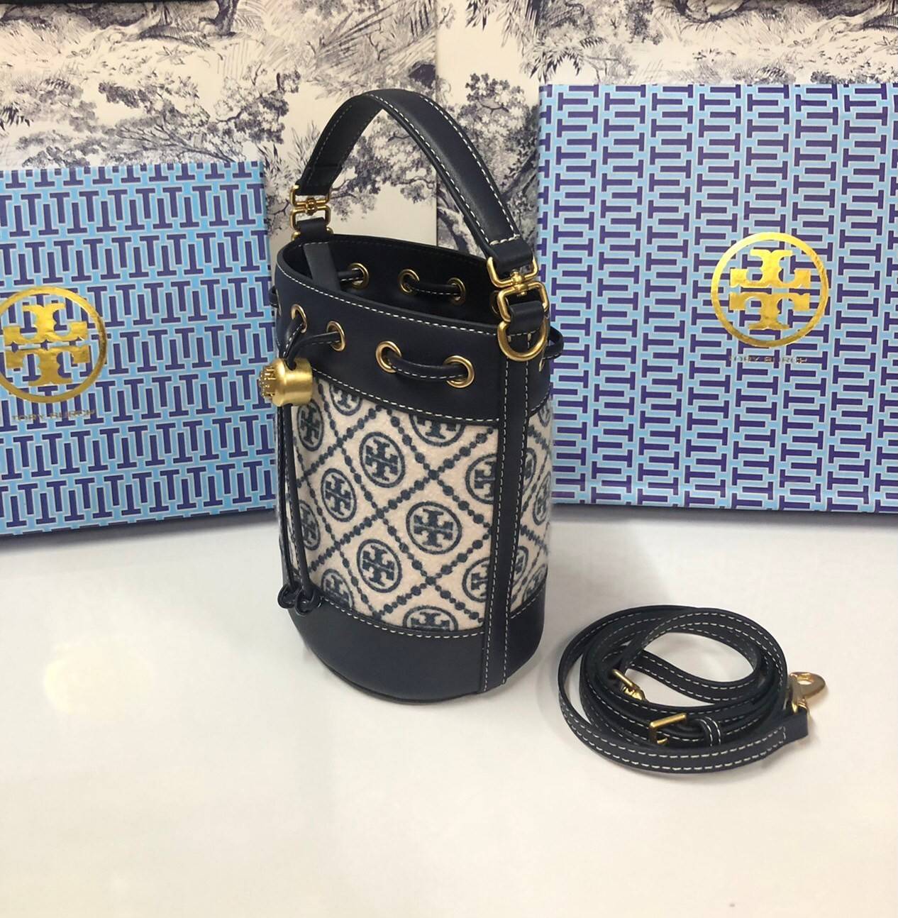 Mini : Tory Burch T Monogram Chenille Bucket Bag เปิดตัวอีกหนึ่งรุ่นกับกระเป๋าลาย T MONOGRAM รุ่นใหม่ล่าสุดจาก TORY BURCH พลาดไม่ได้กับโลโก้สุดคลาสสิก ลวดลาย T Monogram คือวัสดุ chenille หรือที่เรียกว่า ด้านไหมกำมะหยี่ มารังสรรค์ลงบนกระเป๋าBucketใบนี้ เป็