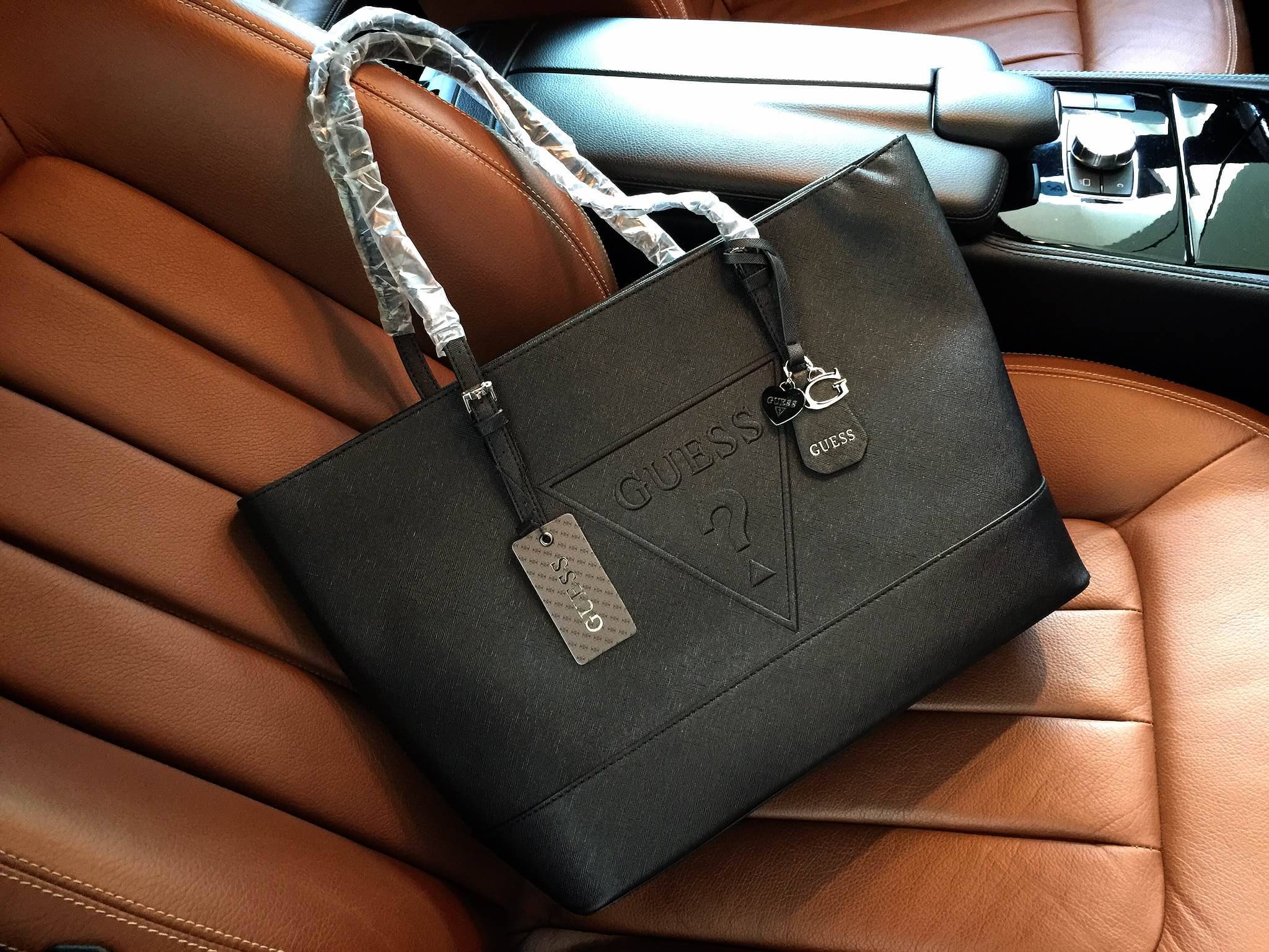 Guess Saffiano Shopping Bag กระเป๋าถือและคล้องบ่าทรงช้อปปิ้งใบใหญ่ หนังSaffiano ใส่เอกสารขนาด A4 ได้ จุของได้เยอะ ด้านหน้าสลักแบรนด์หนังลายนูนพร้อมประดับtagสายหนังถอดออกได้ เปิดปิดด้วยซิปเดียวด้านบน ภายในบุผ้าติดโลโก้ มีช่องเล็กและข่องใส่โทรศัพท์ เรียบง่า