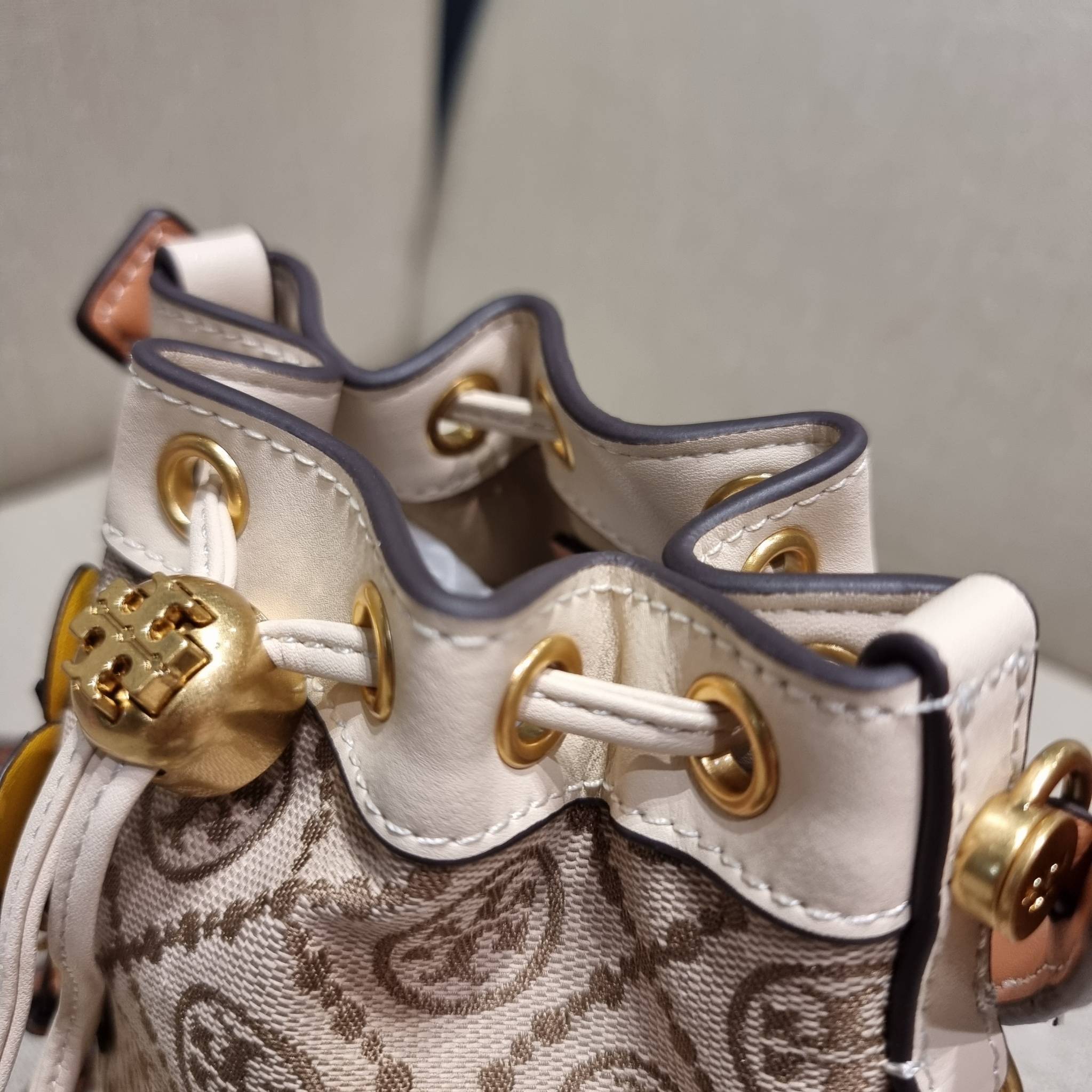 TORY BURCH MINI T MONOGRAM FLORAL BUCKET BAG คอลเลคชั่นใหม่ พร้อมเสิร์ฟความสวยให้ถึงบ้าน!! กระเป๋าบัคเก็ตทรงยอดนิยม ไซส์มินิ ดีไซน์ใหม่ล่าสุด สไตล์งานคราฟ มีลูกเล่นประดับดอกไม้กับตัวกระเป๋า และตัวรูดสาย วัสดุผ้า jacquard ตัดสลับหนังแท้ หูจับและขอบกระเป๋าต