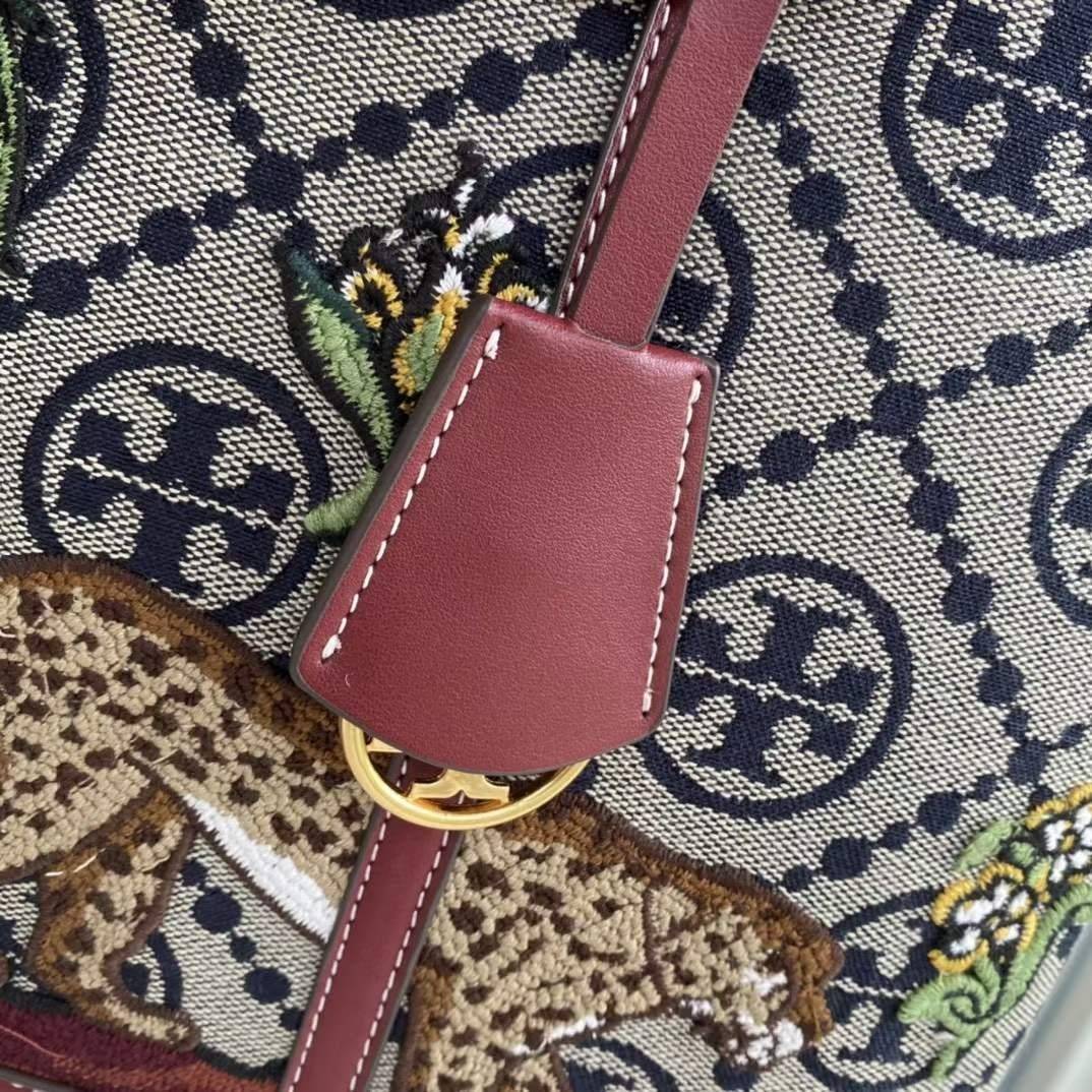 Tory Perry Embroidered T Monogram Triple Compartment Tote Bag เป็นแพทเทิร์นที่ได้รับแรงบันดาลใจจากการควิลท์สไตล์เพนซิลเวเนียดัตซ์ดั้งเดิมและเฉลิมฉลองโลโก้อันเป็นสัญลักษณ์ของแบรนด์ วัสดุผ้าแจ็คการ์ดแบบทอหนัง อะไหล่ทอง โดดเด่นด้วยลายเสือชีร์ต้าร์ งานเย็บปัก