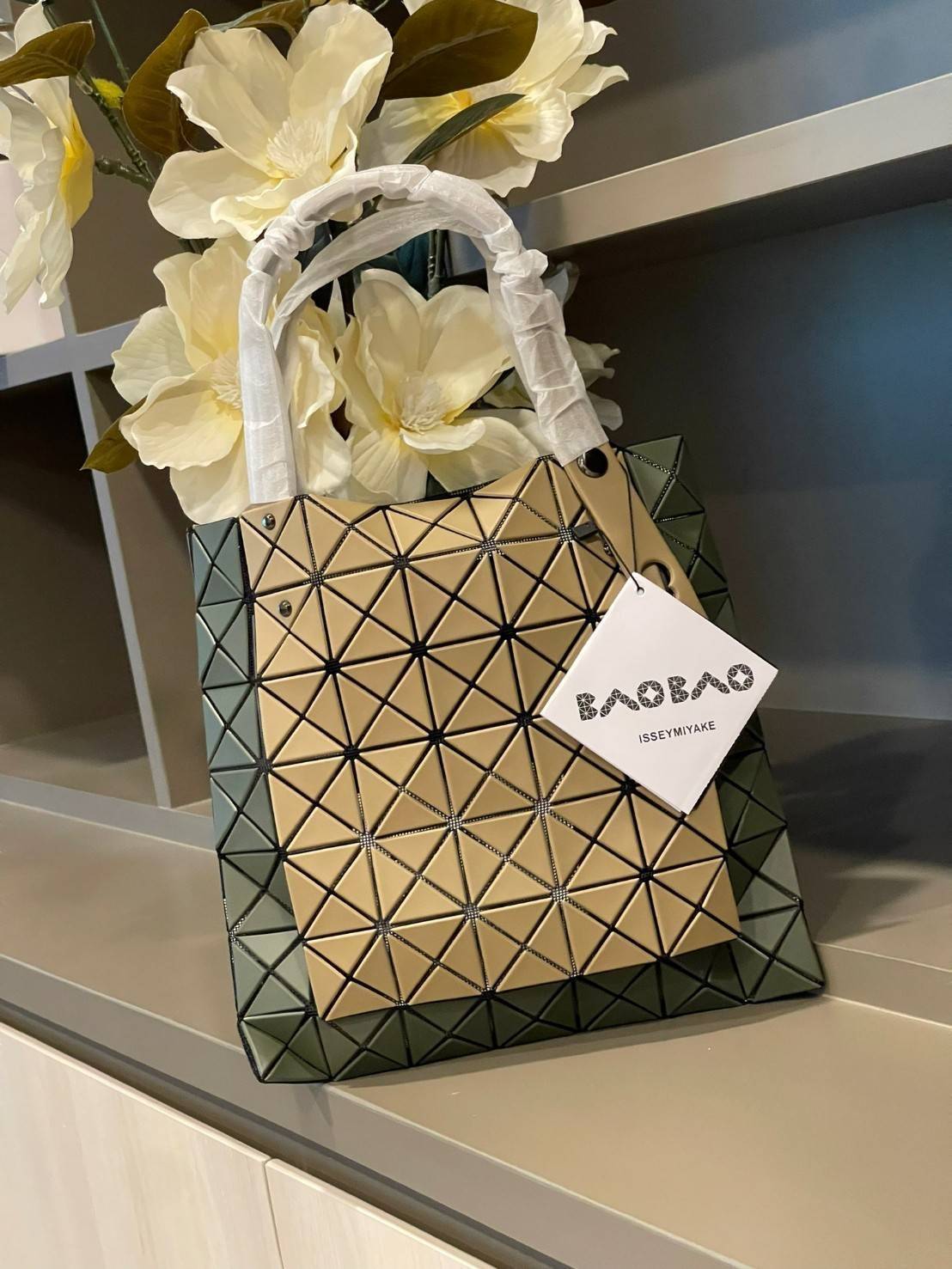 Baobao Issey Miyake Prism Kangaroo tote bag กระเป๋าถือทรงโท้ทที่ประดิษฐ์ขึ้นอย่างเชี่ยวชาญในญี่ปุ่น มาพร้อมแผงเรขาคณิตสำหรับการออกแบบที่ได้รับแรงบันดาลใจจากกระดาษพับ ซิลลูเอทอันเป็นเอกลักษณ์นี้ปิดท้ายด้วยสายรัดแบบอสมมาตร มีการพัฒนาโครงสร้างทรงสามเหลี่ยมเพ