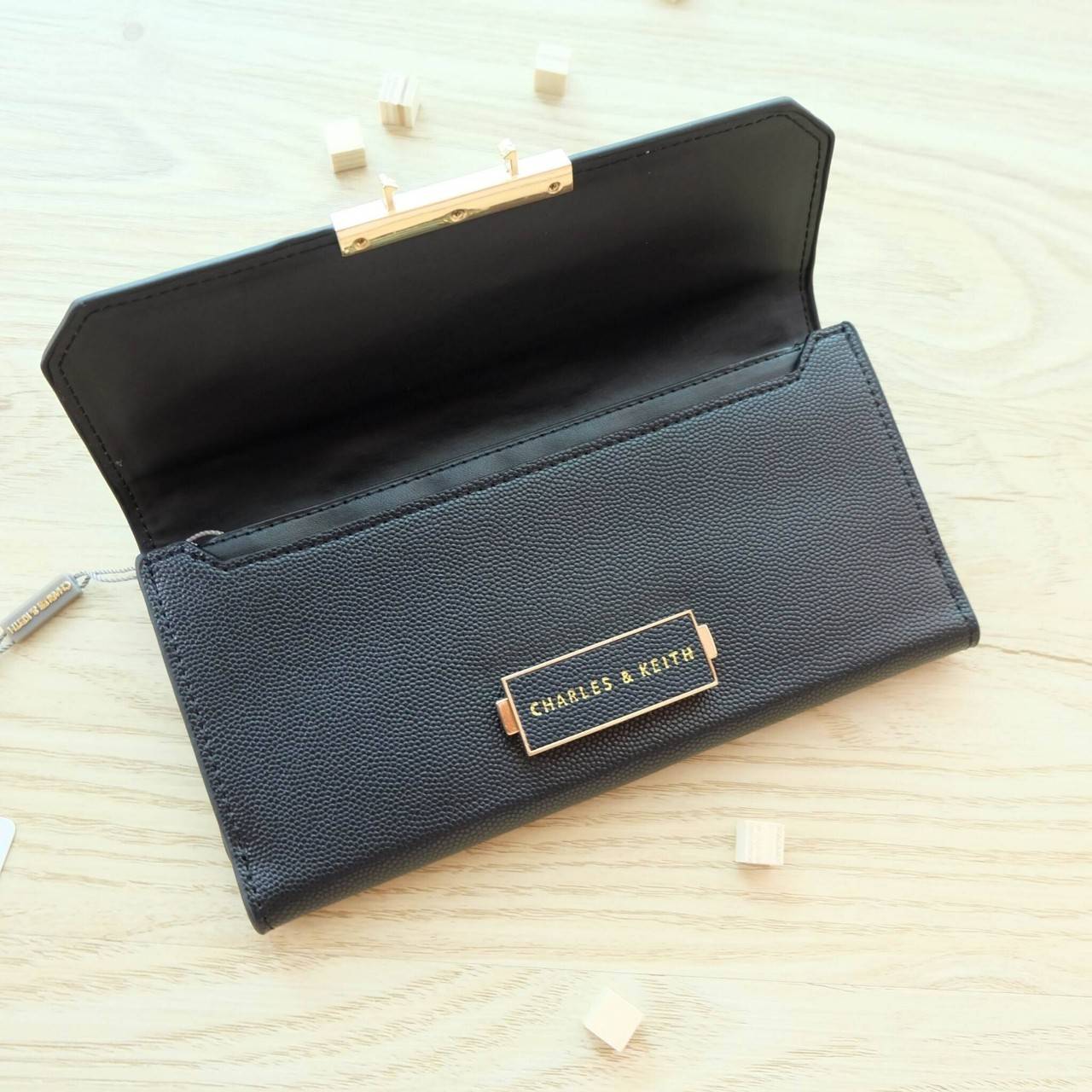 Charles & Keith Push-Lock Long Wallet กระเป๋าเงินใบยาววัสดุหนังลายคาร์เวียร์ ด้านหน้าปั๊มโลโก้แบรนด์ เปิดปิดแบบตัวล็อก ด้านในมีช่องซิปใส่เหรียญและธนบัตร ด้านหลัง มีตัวล็อคแบบกระดุม จุบัตรได้ถึง 12 ใบ รุ่นนี้สวยหรูเกินราคา ด้านหน้าเปิด - ปิดด้วยตัวกดล็อคทั
