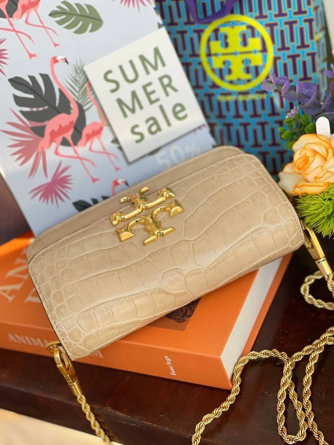 Tory Burch Eleanor Crocodile-Embossed Phone Crossbody Bag จุดเด่นของรุ่นนี้คือดีไซน์ออกมาในสไตล์คลาสสิกที่มาพร้อมกับฮาร์ดแวร์ที่ทำจากวัสดุทองเหลืองและสายสะพายโซ่เกลียวสีทอง ซึ่งการออกแบบได้รับแรงบันดาลใจมาจากเครื่องประดับ รูปทรงกะทัดรัดจึงสามารถสะพายใช้งา