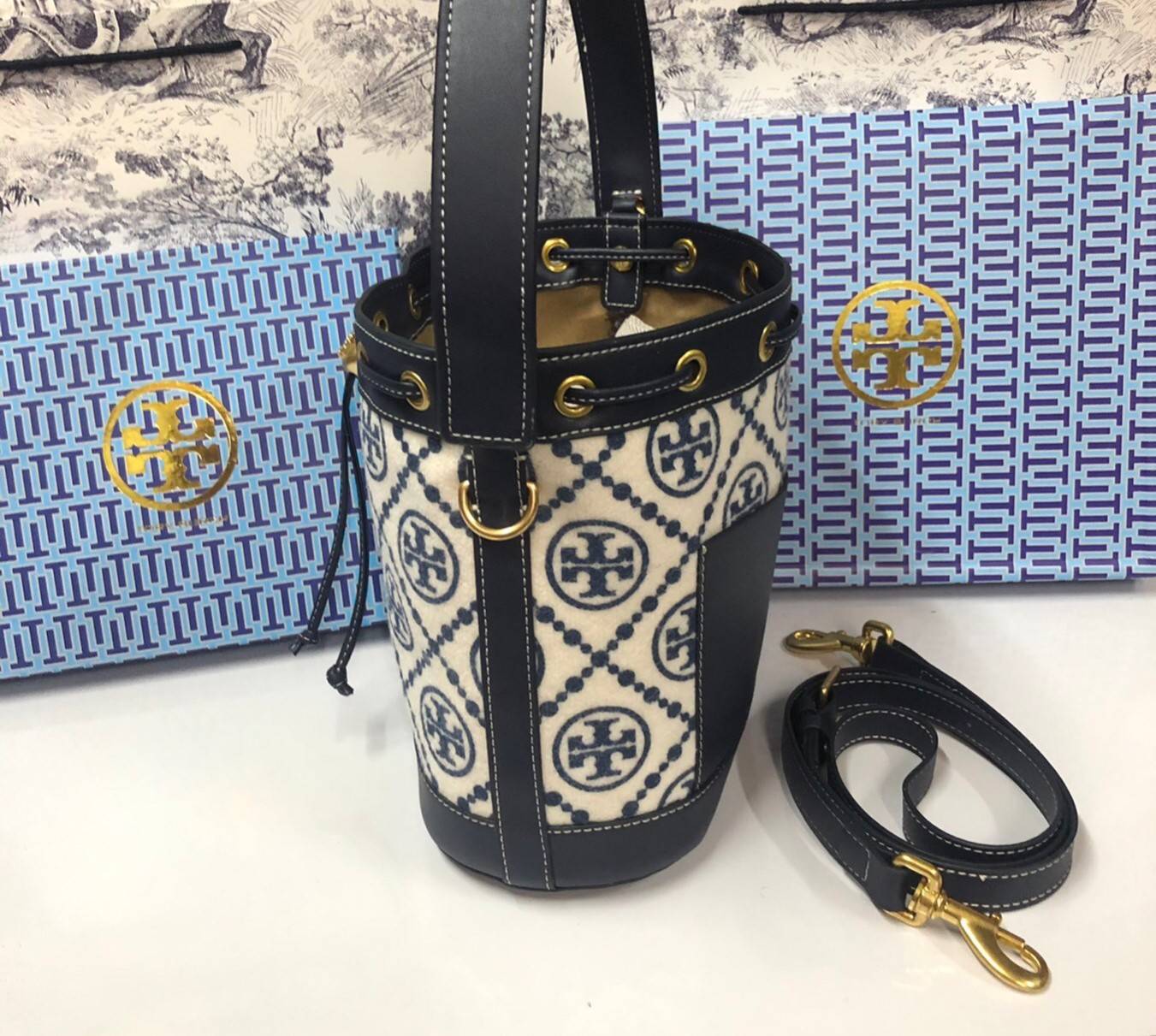 Medium : Tory Burch T Monogram Chenille Bucket Bag เปิดตัวอีกหนึ่งรุ่นกับกระเป๋าลาย T MONOGRAM รุ่นใหม่ล่าสุดจาก TORY BURCH พลาดไม่ได้กับโลโก้สุดคลาสสิก ลวดลาย T Monogram คือวัสดุ chenille หรือที่เรียกว่า ด้านไหมกำมะหยี่ มารังสรรค์ลงบนกระเป๋าBucketใบนี้ เ