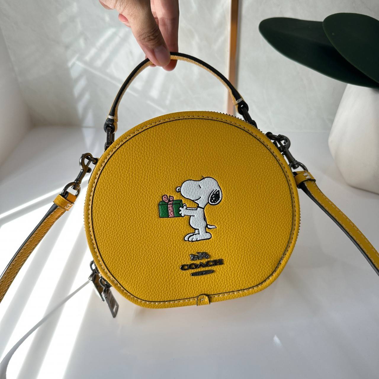 COACH X PEANUTS CANTEEN CROSSBODY WITH SNOOPY PRESENT MOTIF (CE845,CF290) กระเป๋าสะพายข้างทรงกลมไซส์มินิ มีหูจับ วัสหนังแท้ ด้านหน้าโดดเด่นด้วยรูปการ์ตูนSnoopy