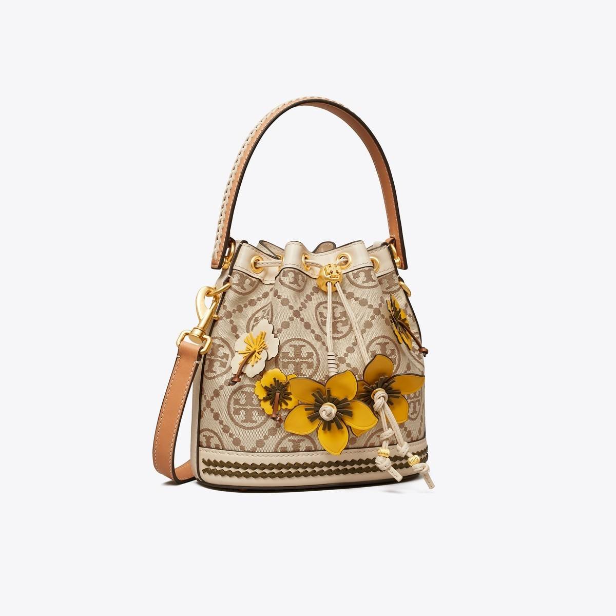 TORY BURCH T MONOGRAM FLORAL BUCKET BAG คอลเลคชั่นใหม่ พร้อมเสิร์ฟความสวยให้ถึงบ้าน!! กระเป๋าบัคเก็ตทรงยอดนิยม ดีไซน์ใหม่ล่าสุด สไตล์งานคราฟ มีลูกเล่นประดับดอกไม้กับตัวกระเป๋า และตัวรูดสาย วัสดุผ้า jacquard ตัดสลับหนังแท้ หูจับและขอบกระเป๋าตกแต่งลายสานสวย