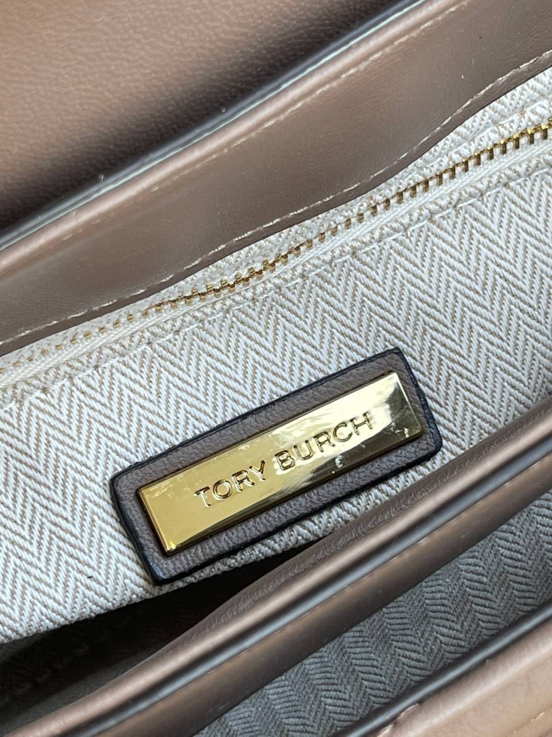 TORY BURCH Kira Chevron Top-handle Satchel กระเป๋าหนังแกะ สัมผัสนุ่มควบคู่กับดีไซน์อันเป็นเอกลักษณ์ กระเป๋าถือทรงสวยที่มีดีไซน์อันเป็นเอกลักษณ์ไม่เหมือนกับที่ไหน ด้วยการตัดเย็บหนังแกะแสนนุ่มแบบลายบุสองชั้น เพิ่มมูลค่าด้วยสายสะพายที่ทำจากโลหะสีทอง อีกทั้งย