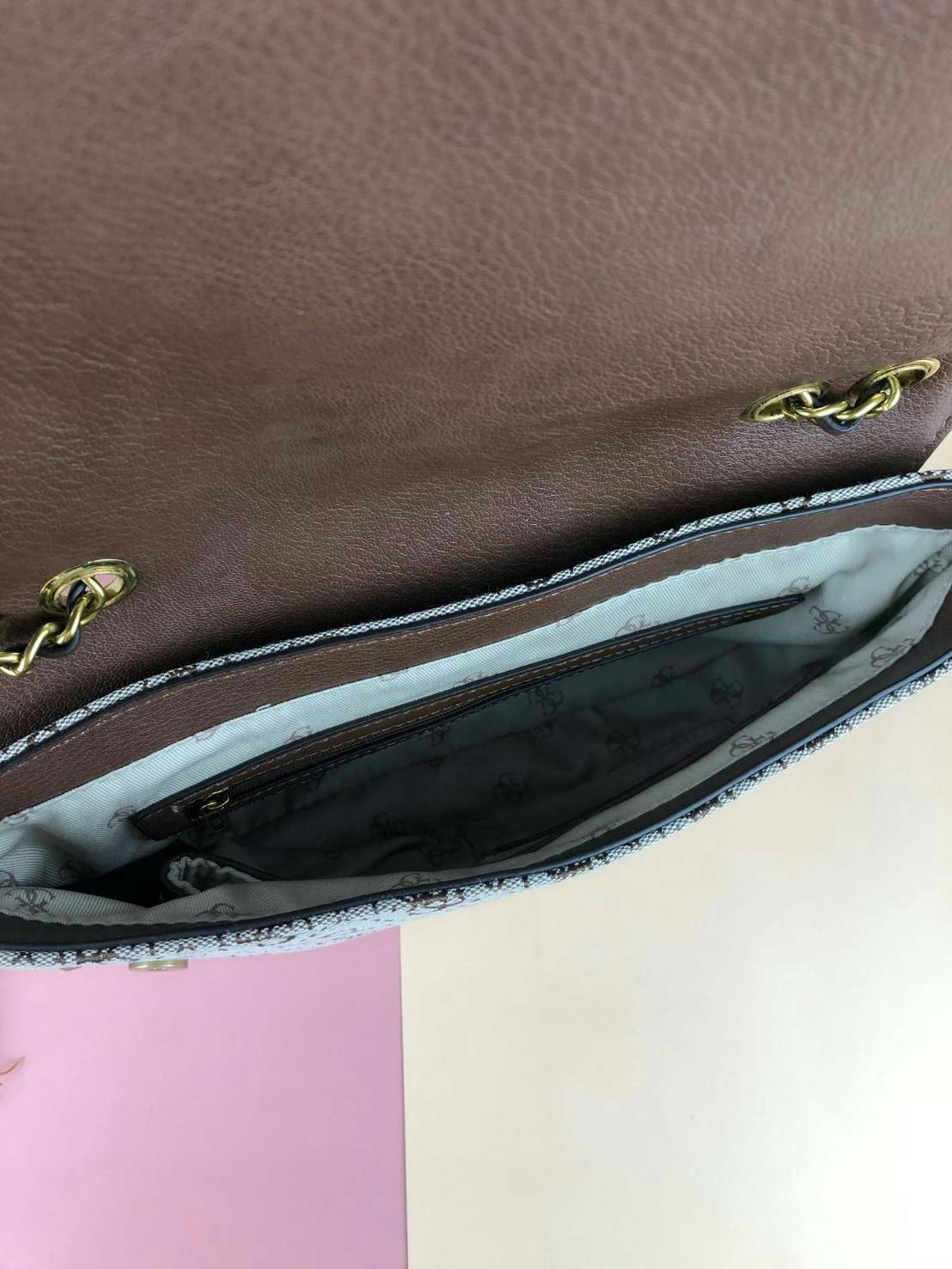 Guess Logo city handbag กระเป๋าสะพายไหล่ ตัวกระเป๋าเป็นผ้าลาย signature ของแบรนด์ ตัดกับหนังที่ตัวขอบกระเป๋า มาพร้อมพวงกุญแจโลโก้แบรนด์ ด้านหน้ามีโลโก้แบรนด์ ด้านหลังมีช่องใส่โทรศัพท์/บัตรได้ เปิดปิดแบบกระดุมแม่เหล็กซ้าย-ขวา ด้านในมีช่องซิป เล็ก 1 ช่อง แล