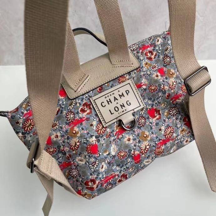 Longchamp X Eu Backpack กระเป๋าเป้สะพายหลังลายดอกๆไม้ วัสดุผ้าฝ้าย อะไหล่สีดำ กระเป๋าเป้แบบลำลองสำหรับสตรีซึ่งนำรูปทรงอันเป็นเอกลักษณ์ของ Le Pliage มาปรับใช้กับทุกสถานการณ์ อุปกรณ์เสริมที่ใช้งานได้จริงนี้มีสายรัดปรับระดับได้และที่จับช่วยให้ สะพายข้างหรือส
