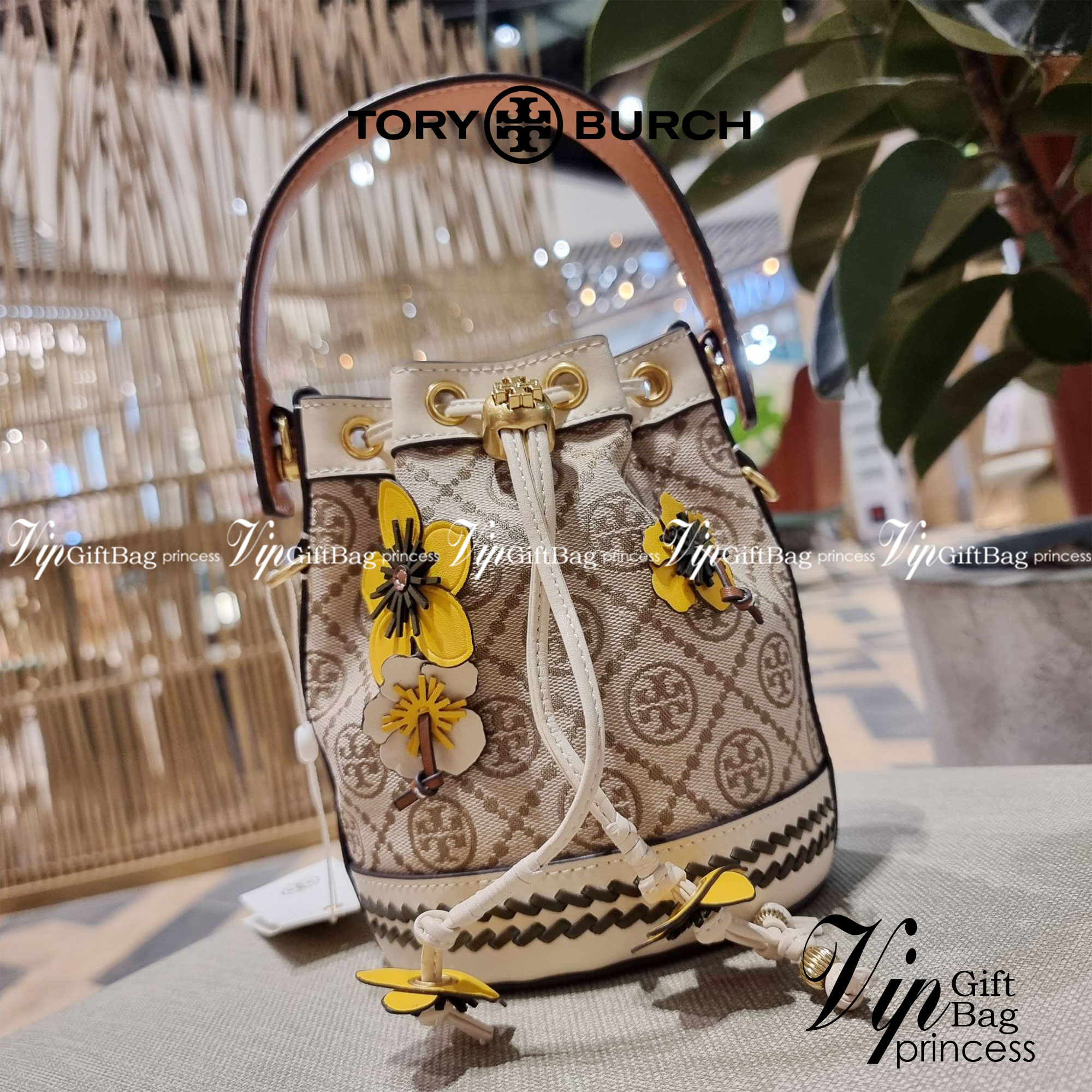 TORY BURCH MINI T MONOGRAM FLORAL BUCKET BAG คอลเลคชั่นใหม่ พร้อมเสิร์ฟความสวยให้ถึงบ้าน!! กระเป๋าบัคเก็ตทรงยอดนิยม ไซส์มินิ ดีไซน์ใหม่ล่าสุด สไตล์งานคราฟ มีลูกเล่นประดับดอกไม้กับตัวกระเป๋า และตัวรูดสาย วัสดุผ้า jacquard ตัดสลับหนังแท้ หูจับและขอบกระเป๋าต