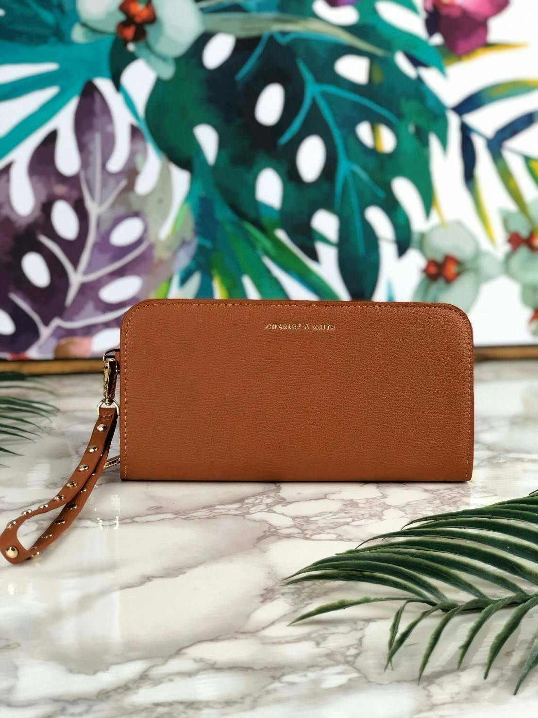 CHARLES & KEITH CLASSIC ZIP AROUND WALLET กระเป๋าเงินใบยาวซิปรอบ มีสายคล้องมีสีเข้ากระเป๋า 1 เส้น ใช้งานง่ายมากๆ คล้องมือก็เก๋ ด้านหน้าปั๊มโลโก้แบรนด์ เปิดปิดด้วยซิปรอบ ที่สายคล้องมือแต่งหมุดสีสวยเด่น ถอดสายได้ จุบัตรได้ 12 ใบ มีช่องซิปใส่เหรียญและช่องใส่
