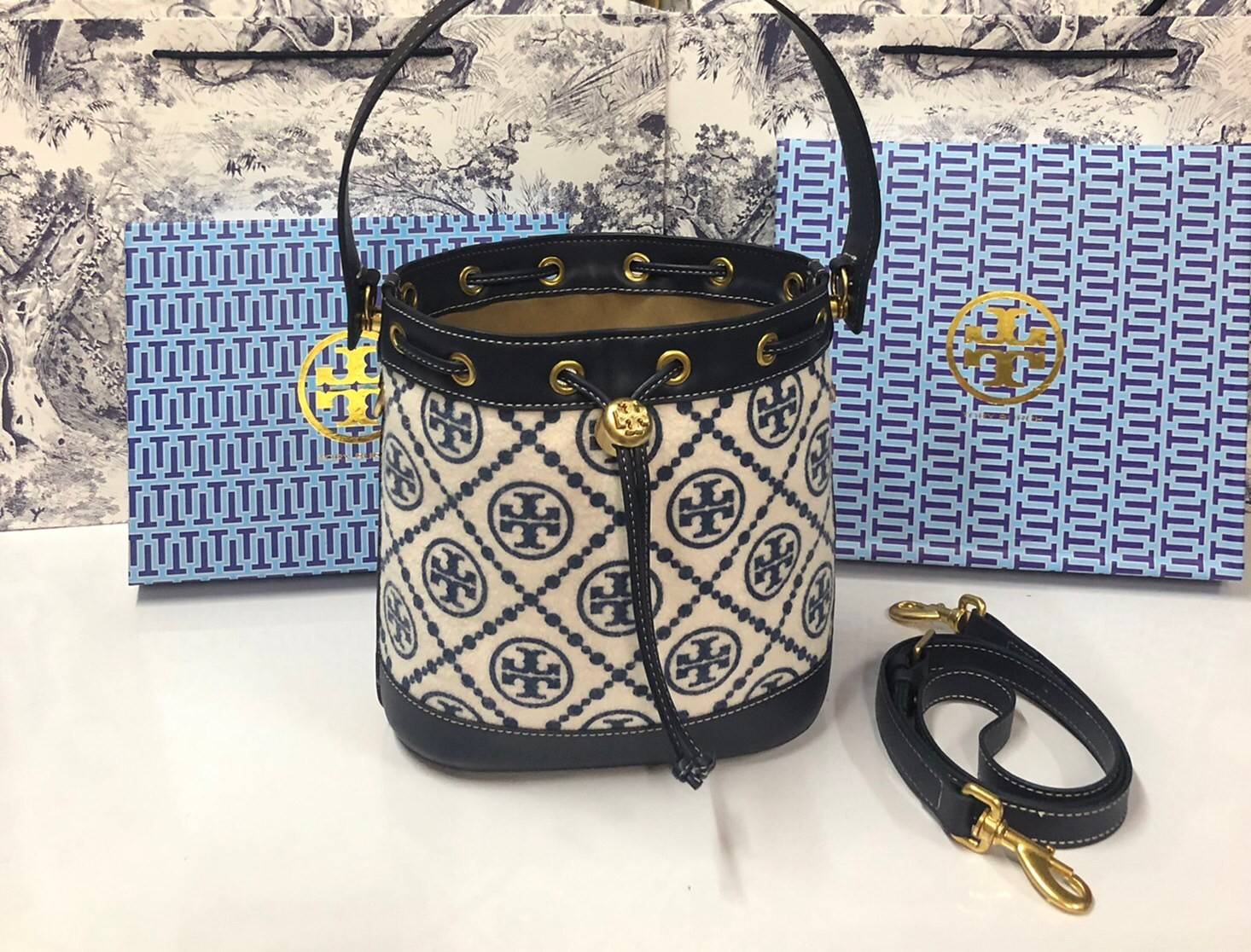 Medium : Tory Burch T Monogram Chenille Bucket Bag เปิดตัวอีกหนึ่งรุ่นกับกระเป๋าลาย T MONOGRAM รุ่นใหม่ล่าสุดจาก TORY BURCH พลาดไม่ได้กับโลโก้สุดคลาสสิก ลวดลาย T Monogram คือวัสดุ chenille หรือที่เรียกว่า ด้านไหมกำมะหยี่ มารังสรรค์ลงบนกระเป๋าBucketใบนี้ เ