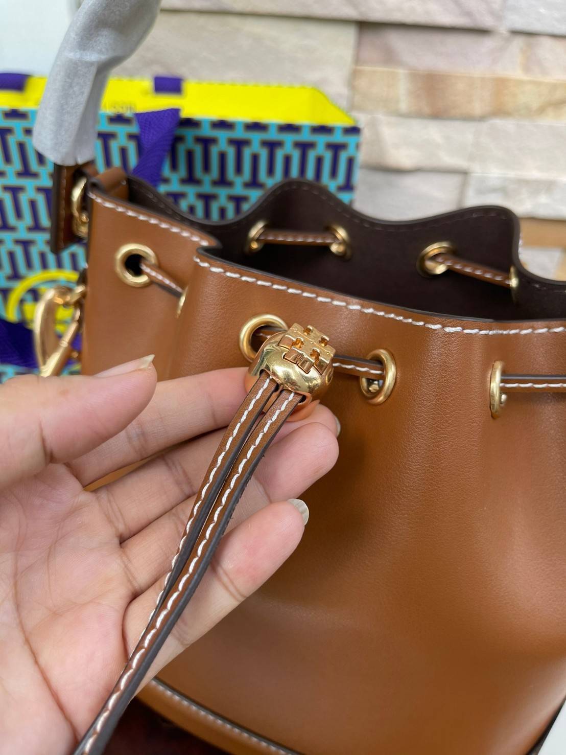 Tory burch T monogram leather bucket bag ดีไซน์สวยงามตามแบบฉบับของแบรนด์แล้ว ยังคงคำนึงถึงการใช้ได้จริงในชีวิตประจำวันอีกด้วย ไม่ว่าจะเป็นกระเป๋าสะพายมาในแบบ Tote Bag ที่ทำจากวัสดุหนังแท้