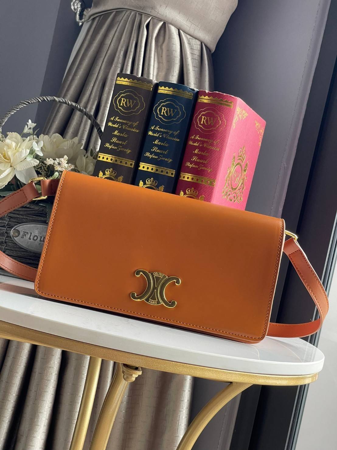 CELINE TRAPEZE TRIOMPHE BAG ดีไซน์เรียบหรู Timeless โดดเด่นมีเอกลักษณ์ ใช้ได้หลายโอกาส แมทช์กับการแต่งตัวง่าย จึงครองใจสาว ๆ ได้ไม่ยาก โดยเป็นกระเป๋าสะพายไหล่ที่อัดแน่นด้วยกลิ่นอายความคลาสสิกและหรูหราตามแบบฉบับของ Celine ด้านหน้าตกแต่งด้วยโลโก้สีทองโดดเด่