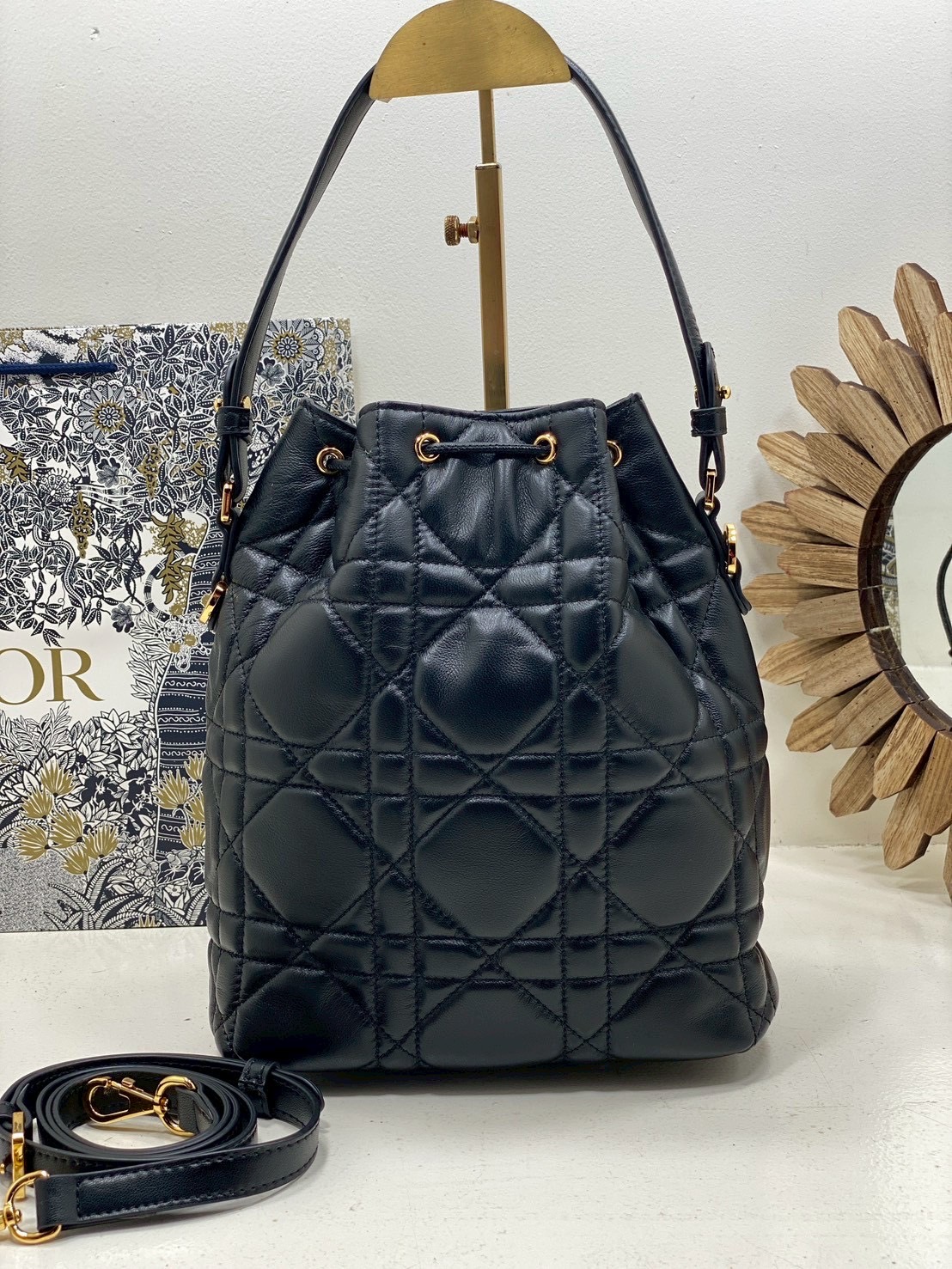 ORI หนังแท้ | Small Dior Caro bucket bag กระเป๋าทรงบักเก็ต รุ่นใหม่ประจำ Fall 2025 โดดเด่นด้วยดีไซน์ที่ทันสมัยและสง่างาม ได้รับการรังสรรค์ขึ้นจากหนังแกะสีดำเดินด้ายลาย Macrocannage พร้อมกับช่องเก็บของขนาดใหญ่แบบเชือกรูดปิด