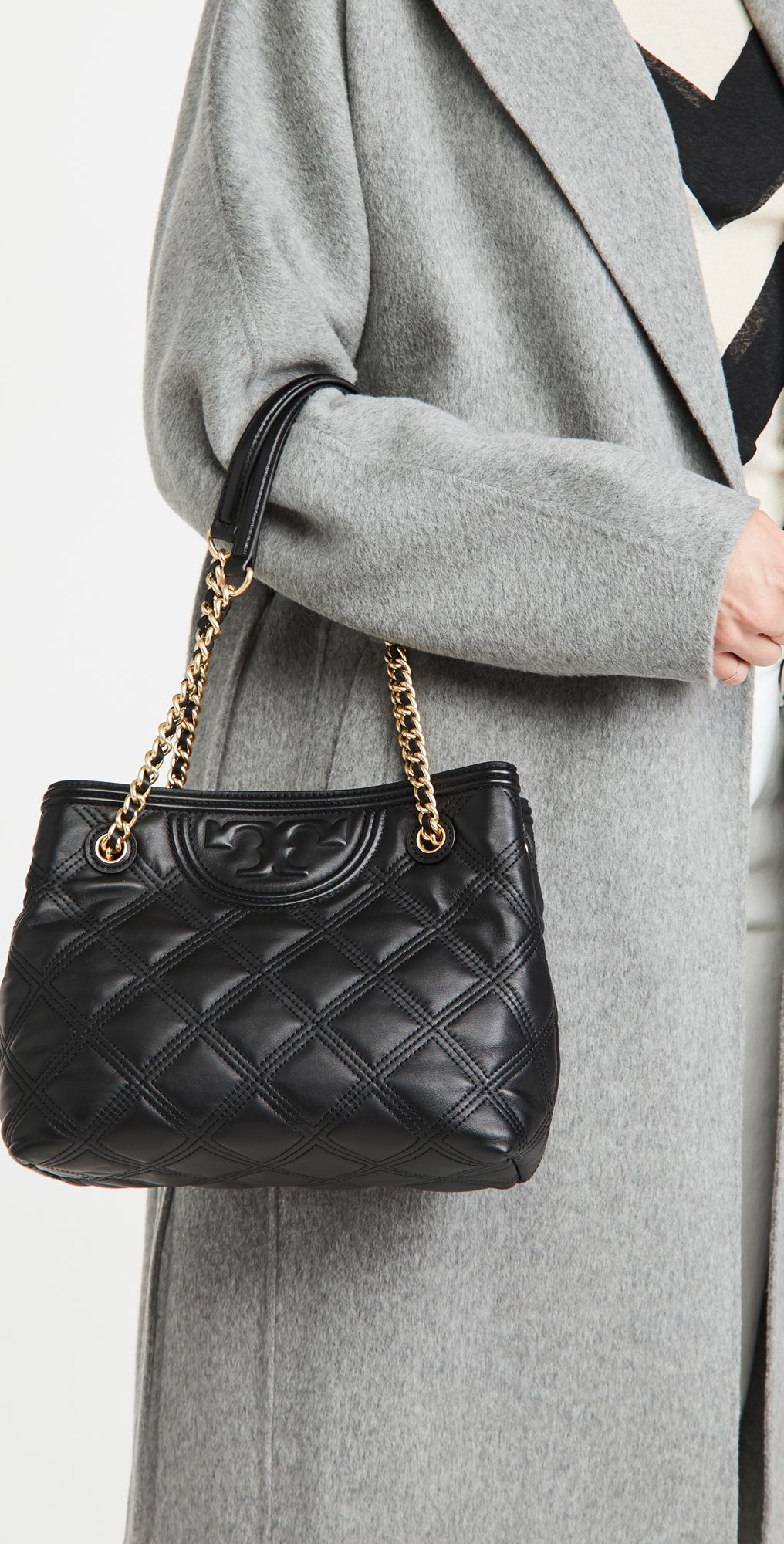 Tory Burch Fleming Soft Small Tote Bag เป็นกระเป๋าสะพายไหล่น่ารัก ๆ สักใบที่มีดีไซน์โดดเด่น สะดุดตา ใน Collection เรียกได้ว่าขายดีอันดับต้น ๆ ของแบรนด์ ใช้ได้ในลุคช์ทางการและกึ่งทางการ ดีเทลการตัดเย็บพิมพ์ลายนูนคู่กับแพทเทิร์นสี่เหลี่ยมทรงเพชร ที่ช่วยเพิ่