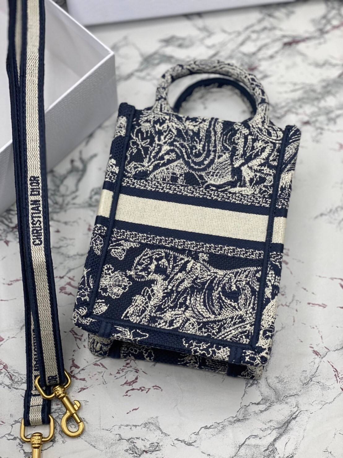 ORI 】Mini Dior Book Tote Phone Bag พร้อมส่งที่ไทย ภาพสินค้าถ่ายจากงานขายจริง ใช้งานต่างประเทศได้ กระเป๋าใบมินิจะใส่โทรศัพท์ได้เช่นเดียวกับของใช้จำเป็นเล็กๆ น้อยๆ ในแต่ละวัน มาพร้อมสายสะพายไหล่แบบปักที่ปรับได้และถอดออกได้ อุปกรณ์เสริมอันทันสมัยนี้สามารถสวม