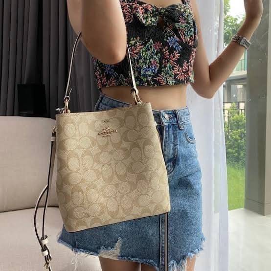 COACH SMALL TOWN BUCKET BAG IN SIGNATURE สำหรับสาวแฟชั่นที่ชอบรายละเอียดชิคๆ ดีไซน์สุดเก๋ แนะนำเลยสำหรับกระเป๋าทรงบักเก็ตใบนี้ เชื่อว่าสาว ๆ หลายคนชื่นชอบ เป็นไอเทมที่สามารถแมทช์ได้กับเสื้อหลากหลายสไตล์ บรรจุของได้เยอะโดยที่กระเป๋าไม่เสียทรง แบ่งช่องใช้งา