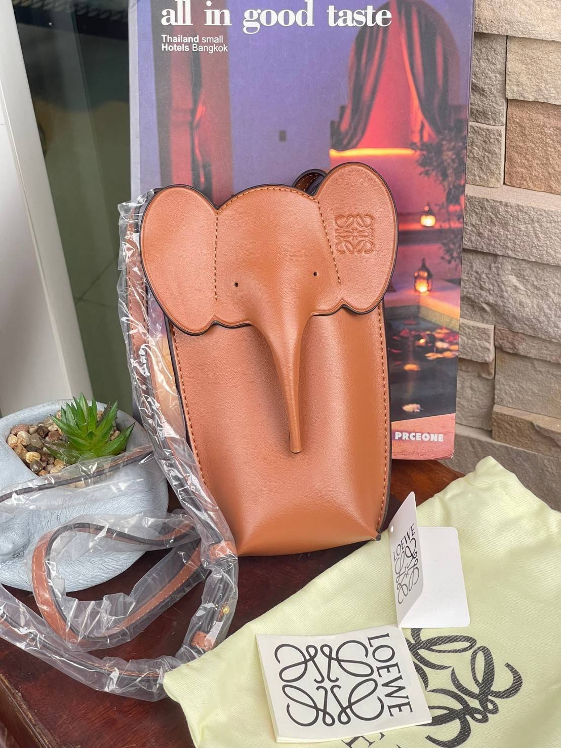 Loewe Leather Elephant Phone Holder แบรนด์หรูจากประเทศสเปนอย่าง โลเอเว่ (LOEWE) หลายๆคนคงนึกถึงกระเป๋ารูปทรงช้างขนาดเล็ก ที่เป็นเหมือนหนึ่งในซิกเนเจอร์ของแบรนด์ มีทั้งแบบสะพายข้าง แบบถือ รวมไปถึงในแบบเครื่องหนังชิ้นเล็กอย่างกระเป๋าใส่มือถือรุ่นนี้ ผลิตจาก