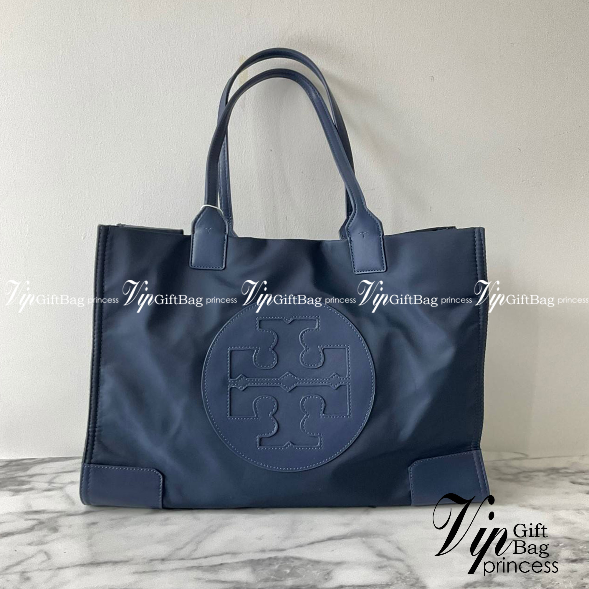กระเป๋าทรงโท้ทใบใหญ่ TORY BURCH ELLA TOTE BAG วัสดุ NYLON ทั้งใบตัดด้วยหนังสีดำ แต่งโลโก้แบรนด์ด้านหน้า ด้านข้างมีกระดุม สามารถขยายทรงได้ ด้านในเปิดปิดด้วยกระดุมแม่เหล็กฝัง ช่องกว้างหลักหนึ่งช่องและช่องซิปอีกช่อง สามารถใส่แล็ปท็อปได้สบาย ใบใหญ่เว่อวัง ไอเ