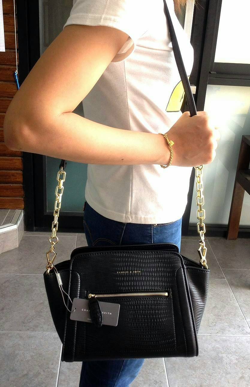 CHARLES & KEITH TRAPEZE CROSSBODY BAG กระเป๋าถือหรือสะพายดีไซน์ยอดนิยมหนังอยู่ทรงสวย ด้านหน้าสกรีนโลโก้ และมี 1 ช่องซิป เปิดปิดด้วยซิป ภายในมีช่องใส่ของ และช่องซิปเล็ก ใส่กระเป๋าสตางค์ใบยาว มือถือ ของใช้ได้เยอะ พร้อมสายสะพายยาวโซ่ต่อหนังปรับได้ถอดได้ มีหม